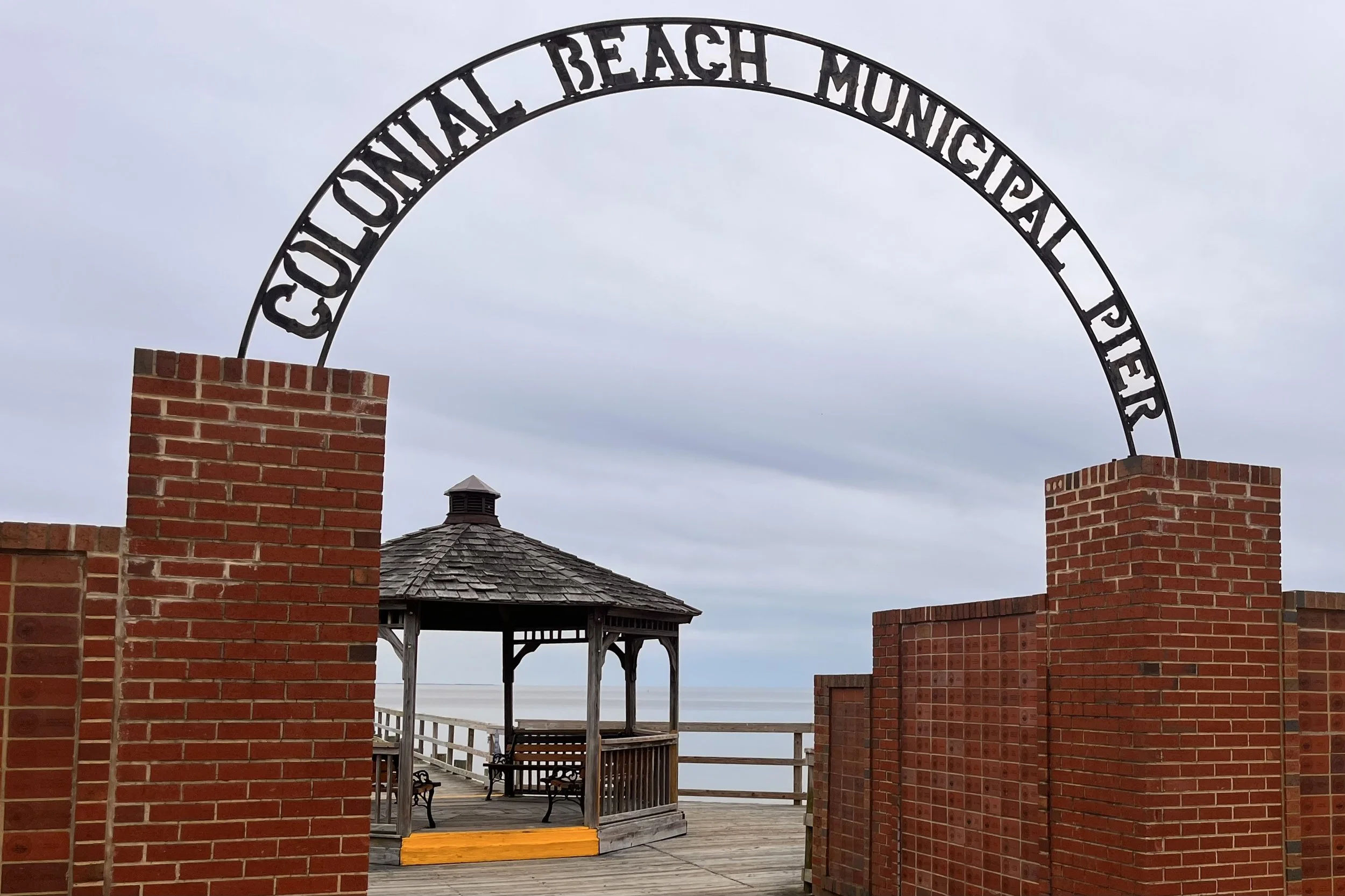 Entrance arch to Colonial Beach Municipal Pier with gazebo and waterfront boardwalk along the Potomac River in Colonial Beach Virginia.