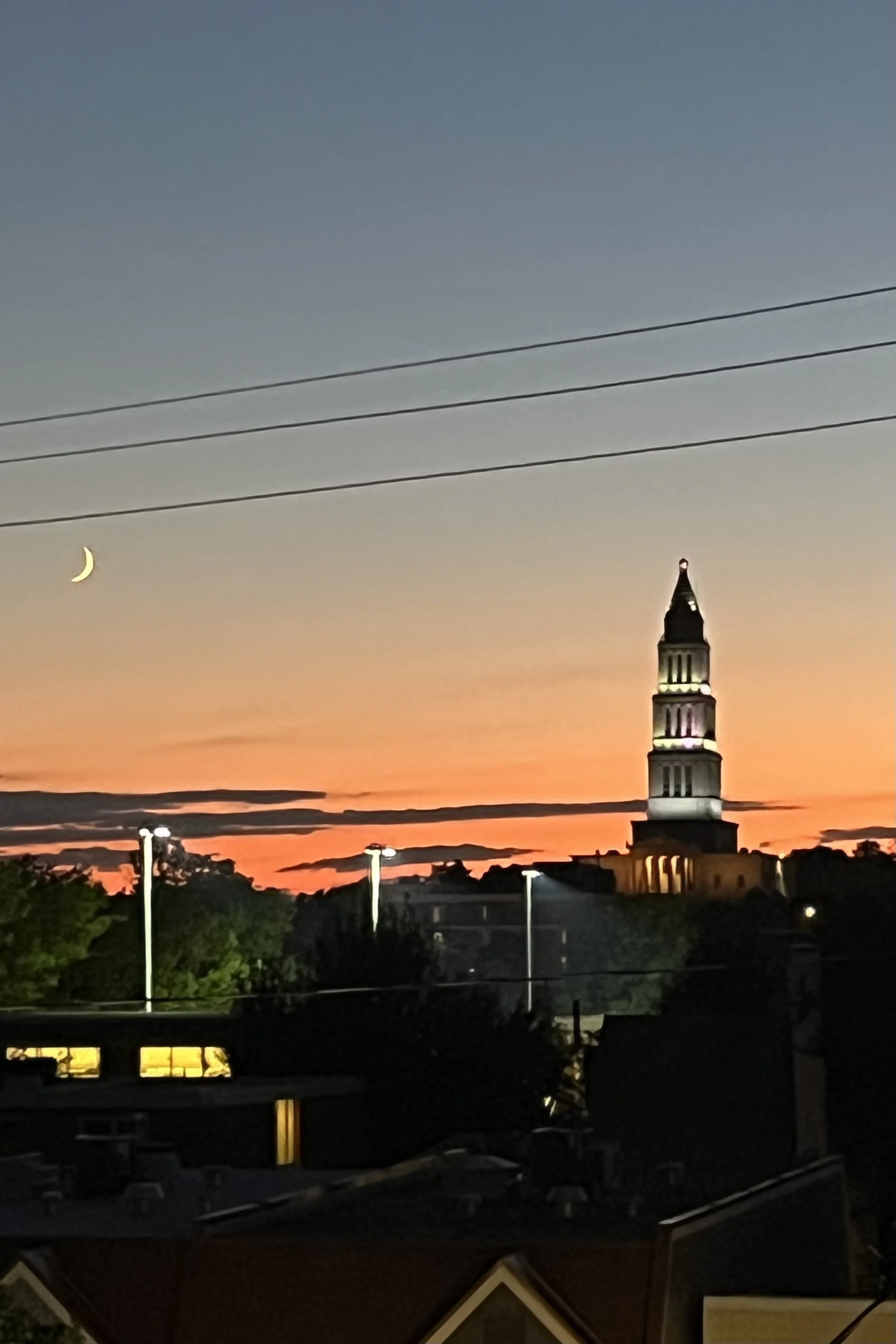Crescent moon and sunset sky beside the George Washington Masonic Memorial tower above Old Town Alexandria rooftops.