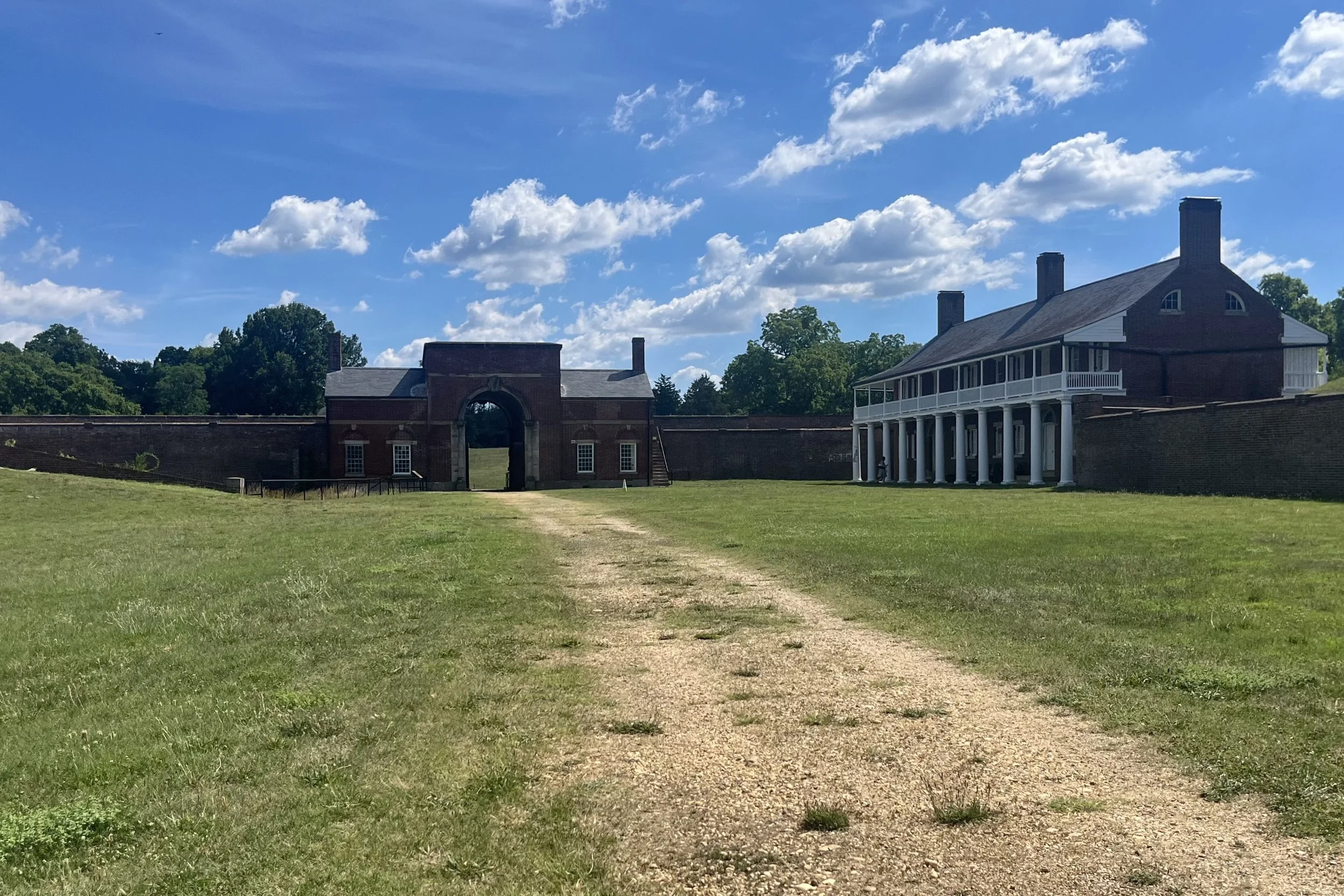 Open courtyard inside Fort Washington featuring historic brick buildings, grassy grounds, and a central path leading across the fort.