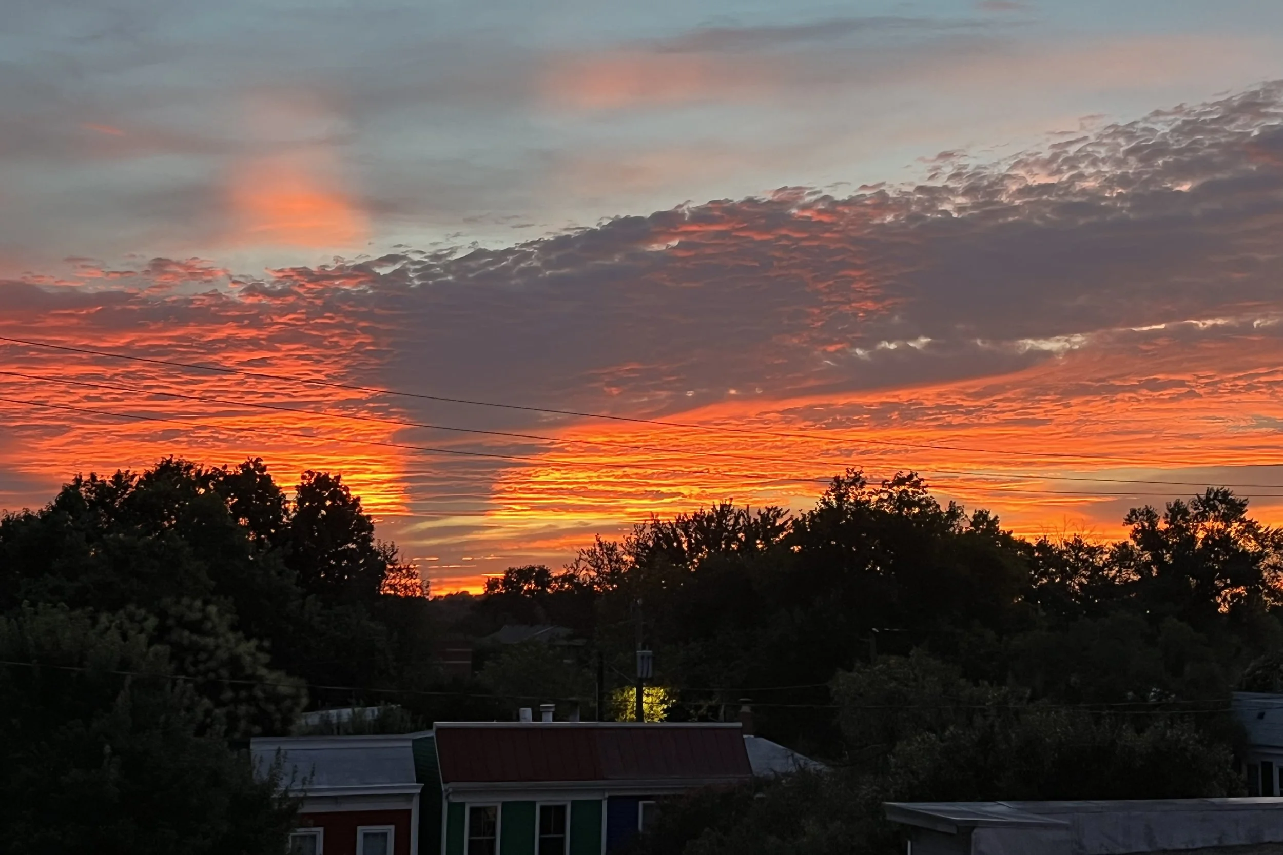 Bright orange sunset clouds stretching across the sky above rooftops in Old Town Alexandria.