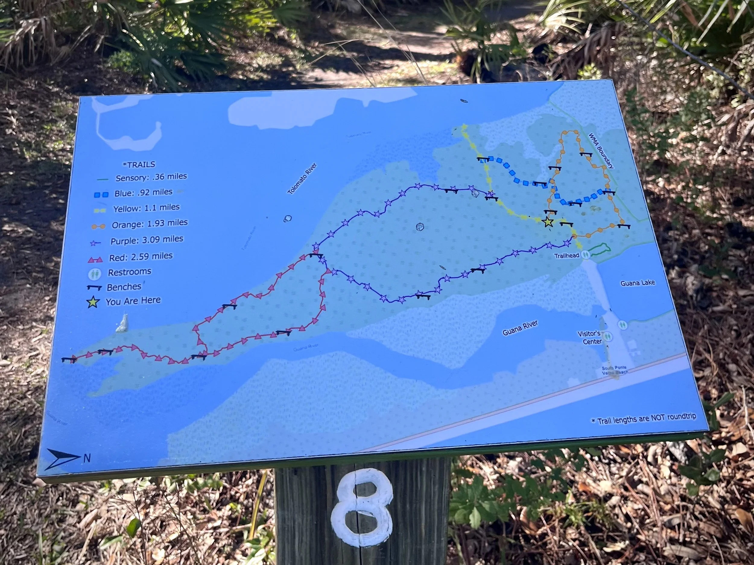 Trail map sign showing multiple color-coded hiking routes and distances at the Guana Tolomato Matanzas Reserve.