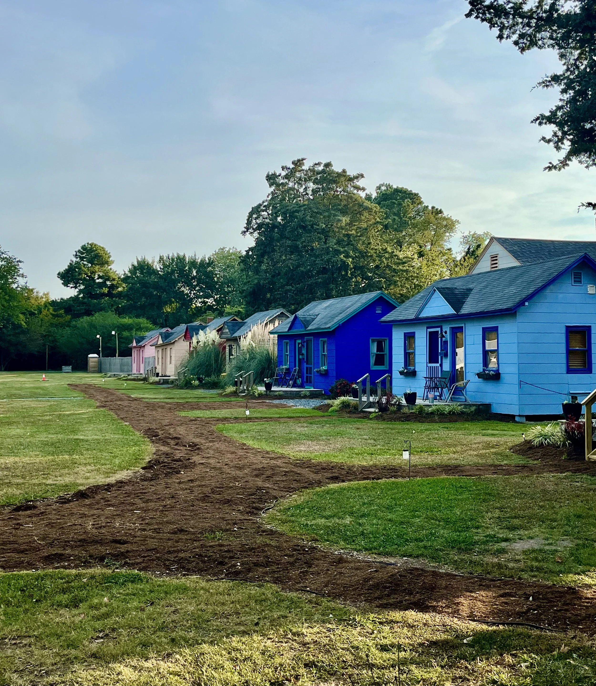 Row of small colorful tiny houses with a grassy path running through the center.