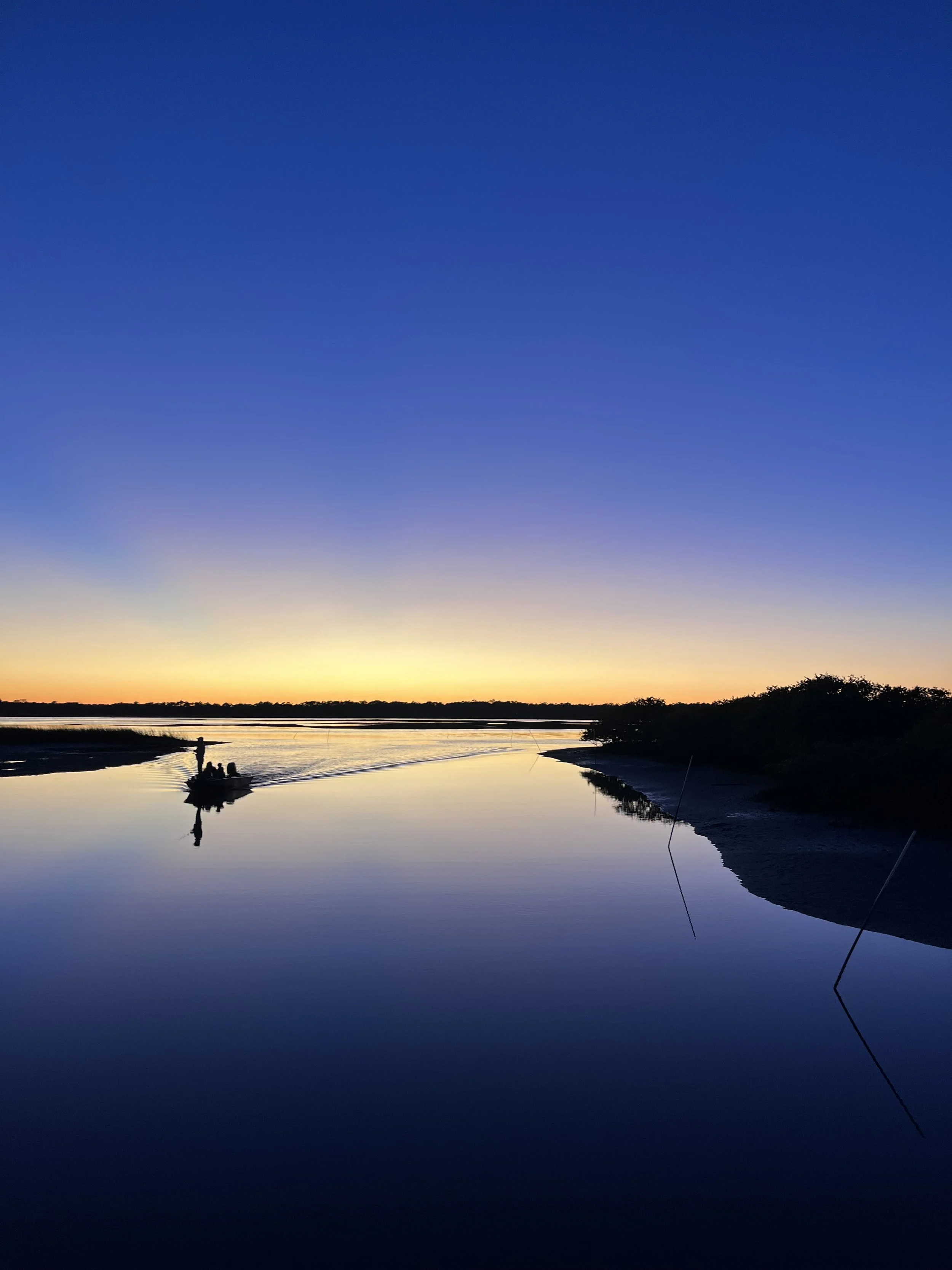 Calm water at sunset in St. Augustine with a silhouetted boat and fading light.