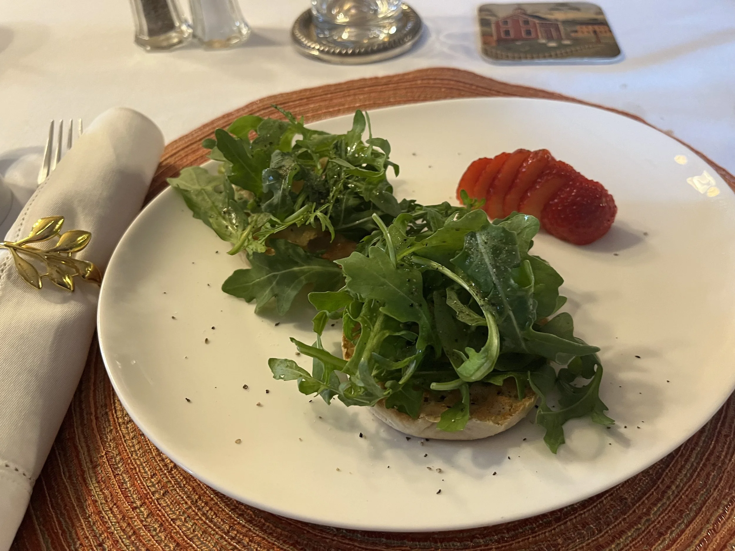 Open-faced whole-wheat muffin topped with arugula dressed in olive oil and salt.