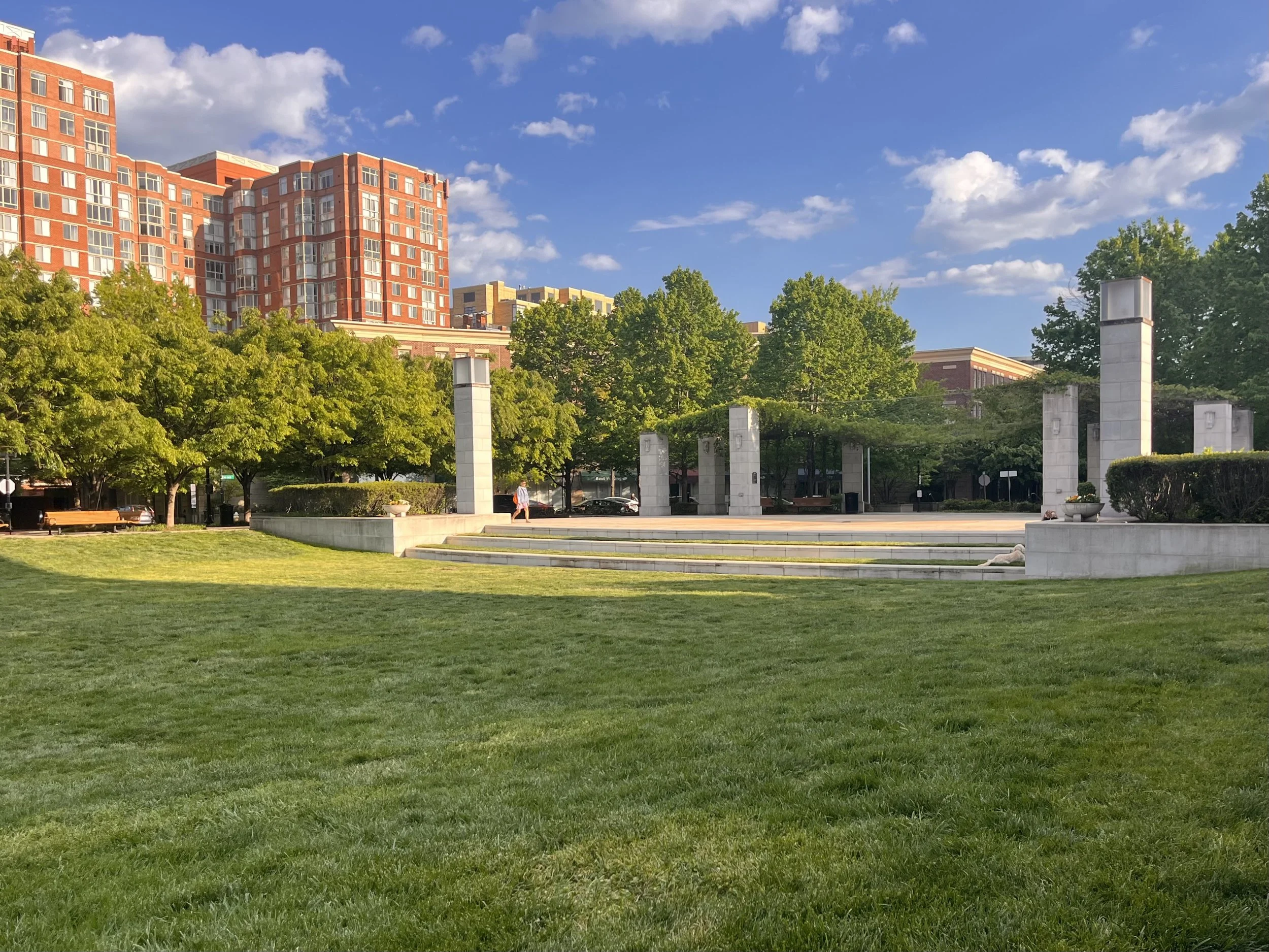 John Carlyle Square in Alexandria with an open lawn, surrounding seating, and stone columns around the central plaza