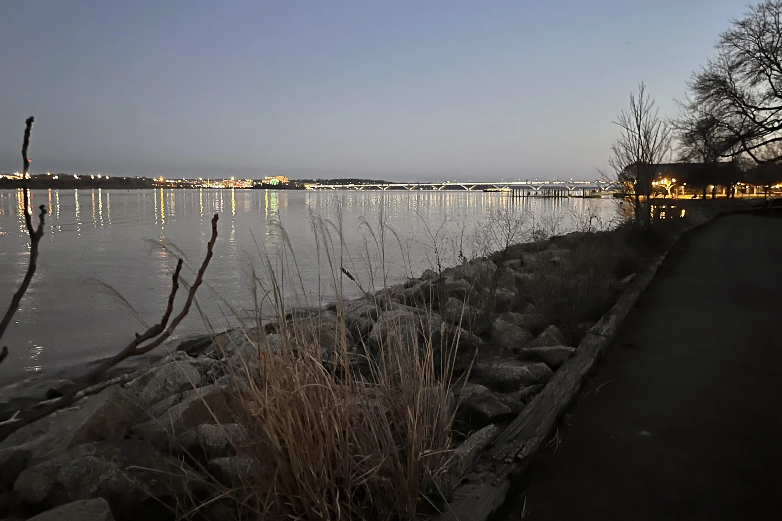 Empty canal-side path at Tide Lock Park with water and rocks alongside at dusk