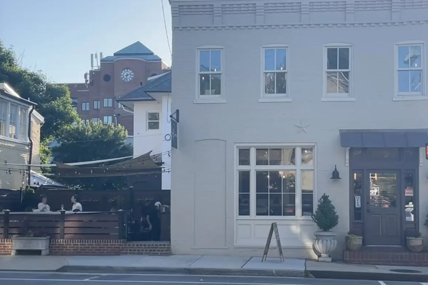Exterior view of La Pluma patio in Old Town Alexandria with string lights and outdoor dining along a quieter side street.
