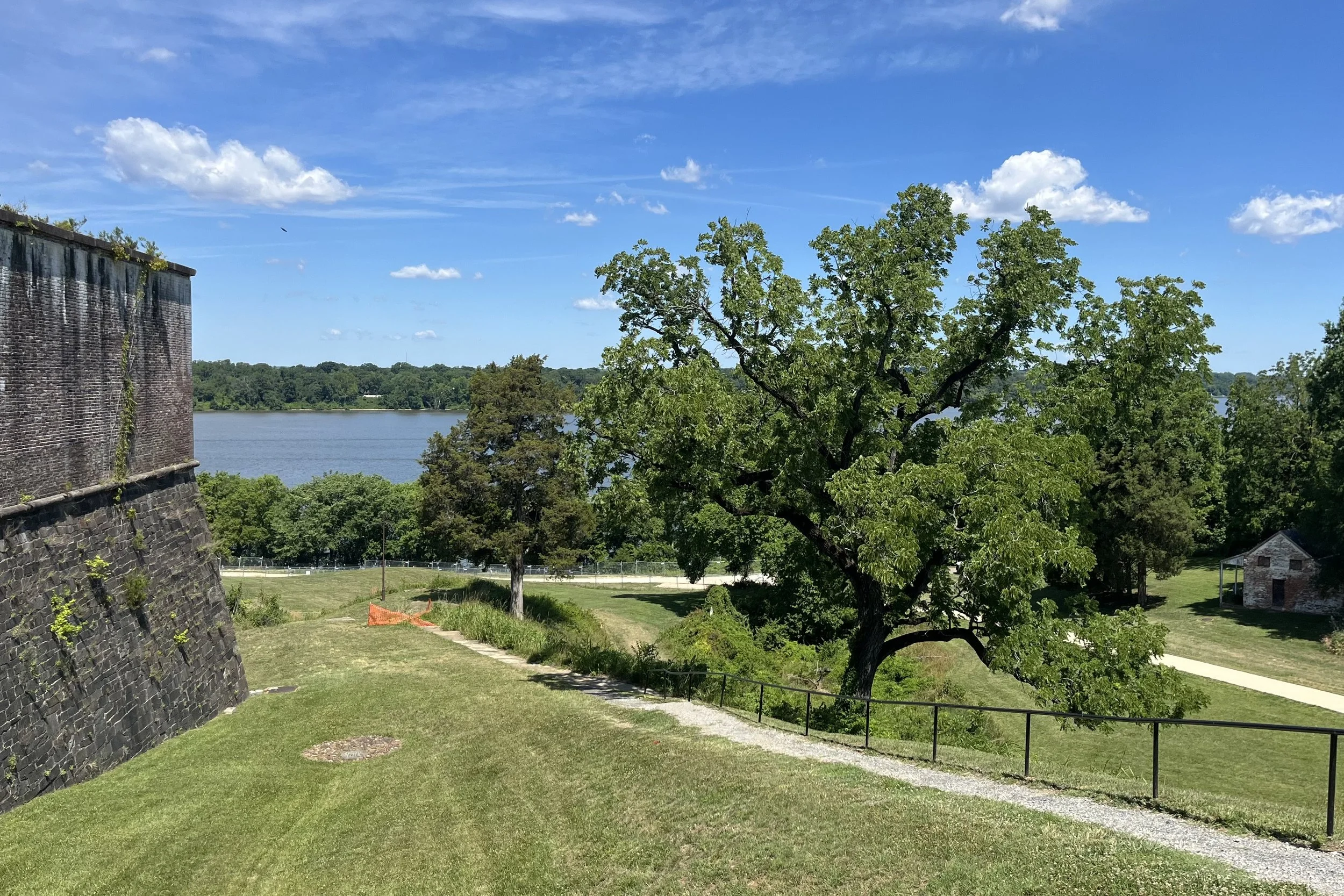 Potomac River overlook at Fort Washington Park showing historic fort walls, open lawns, mature trees, and river views on a clear summer day.