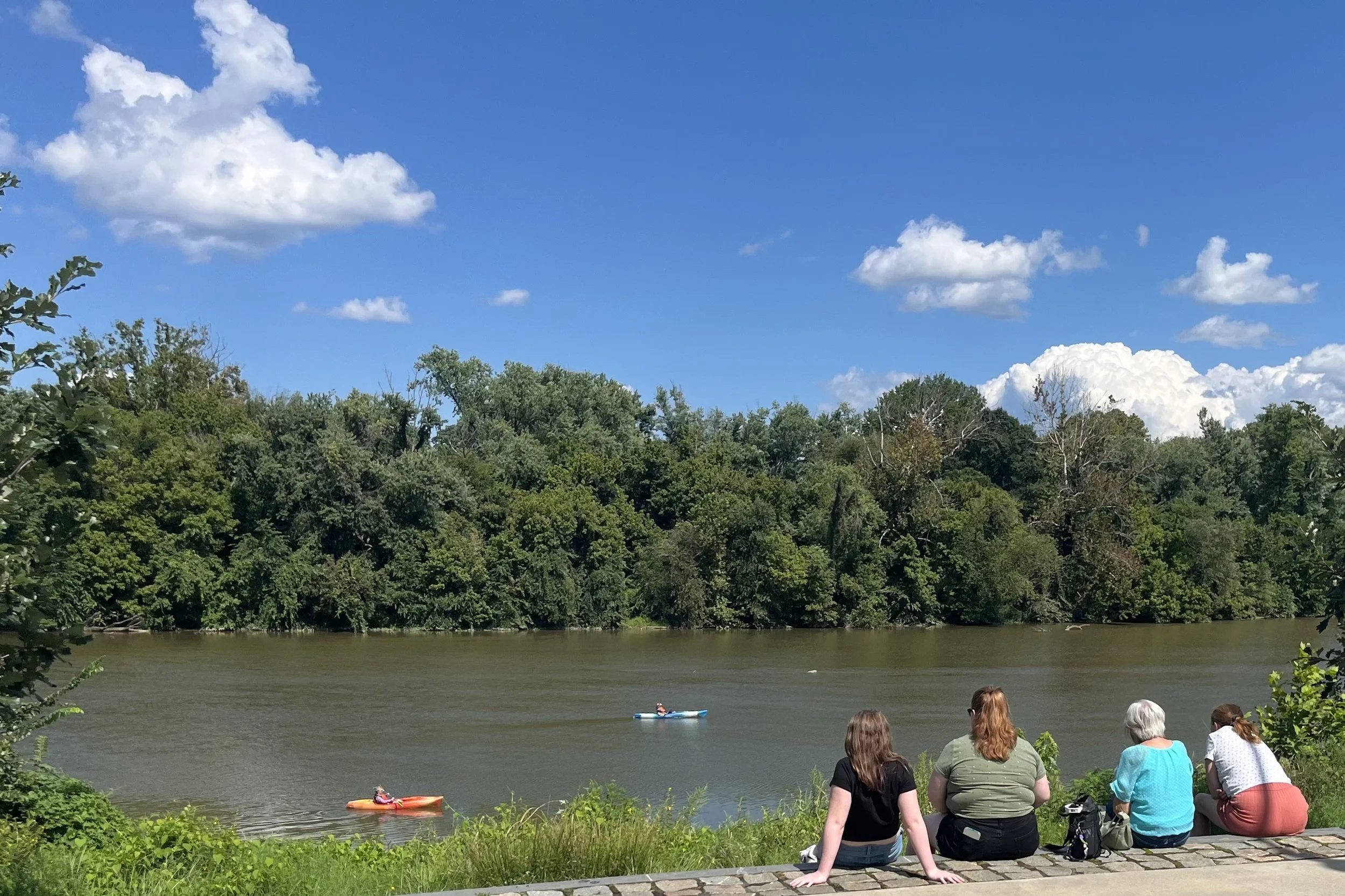 Visitors watching kayakers on the Rappahannock River at Riverfront Park in Fredericksburg, Virginia.