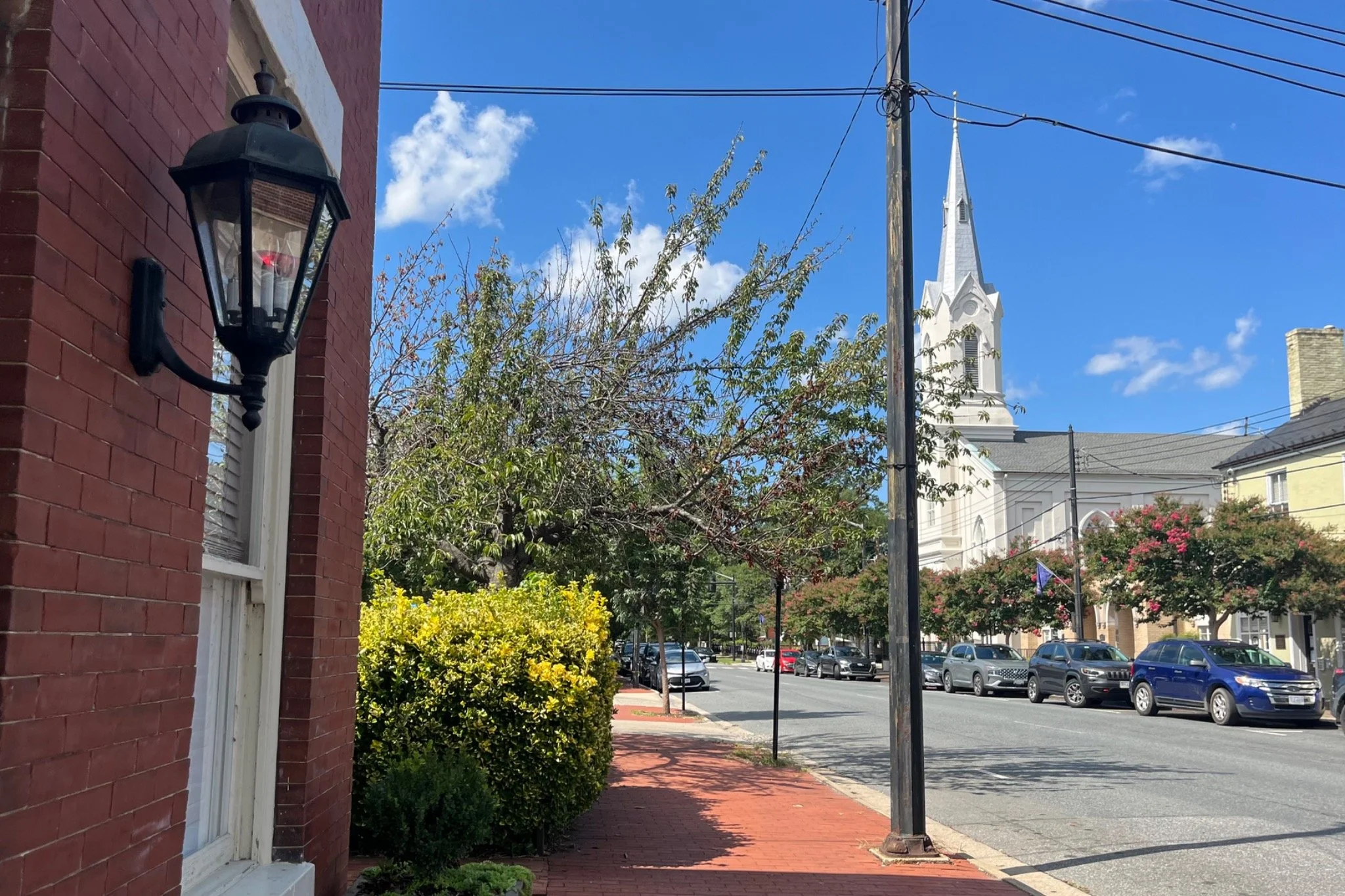 Traditional lantern on a red-brick building overlooking a white church steeple in downtown Fredericksburg, Virginia.