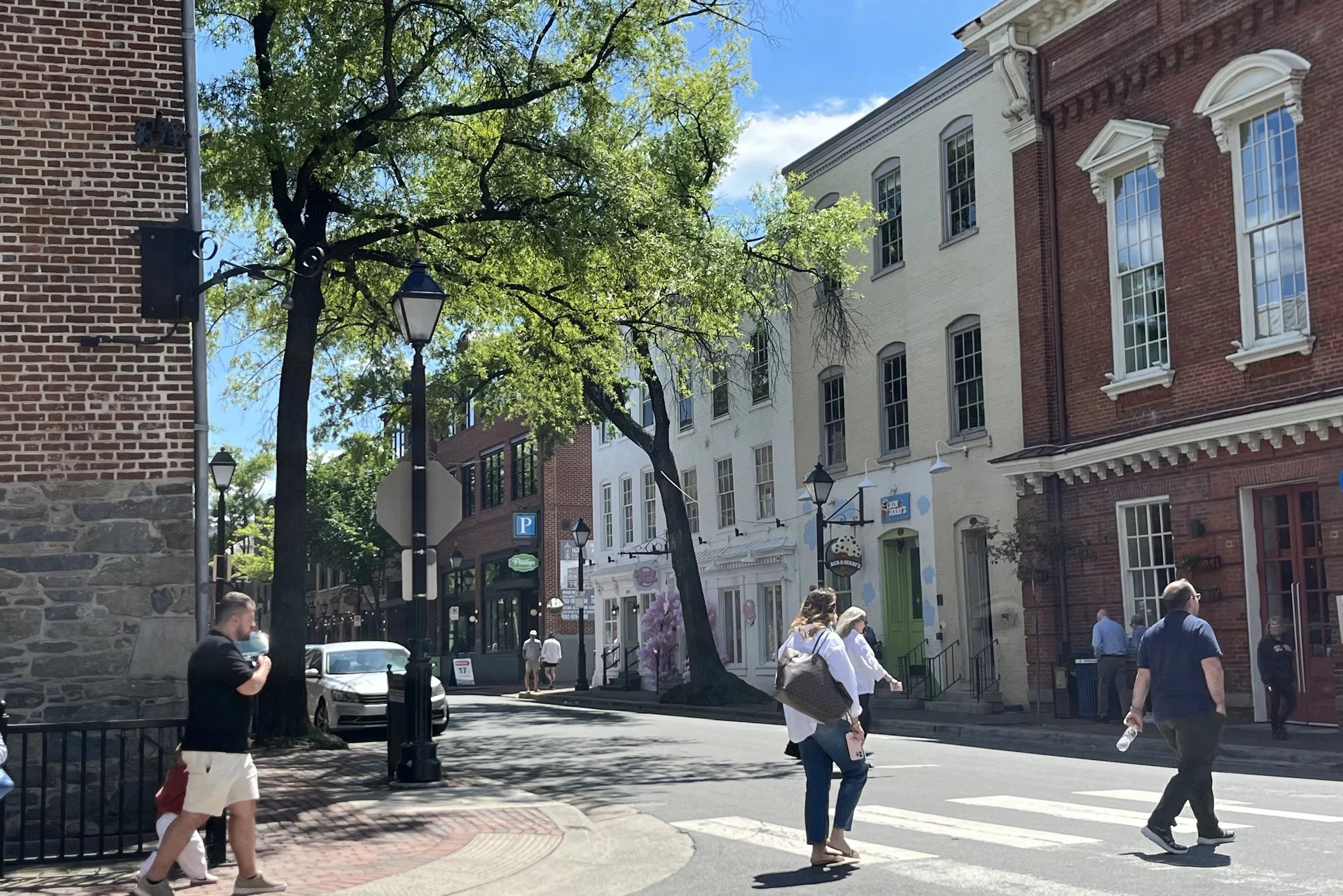 Historic buildings, brick sidewalks, and pedestrians along King Street in Old Town Alexandria on a sunny day.