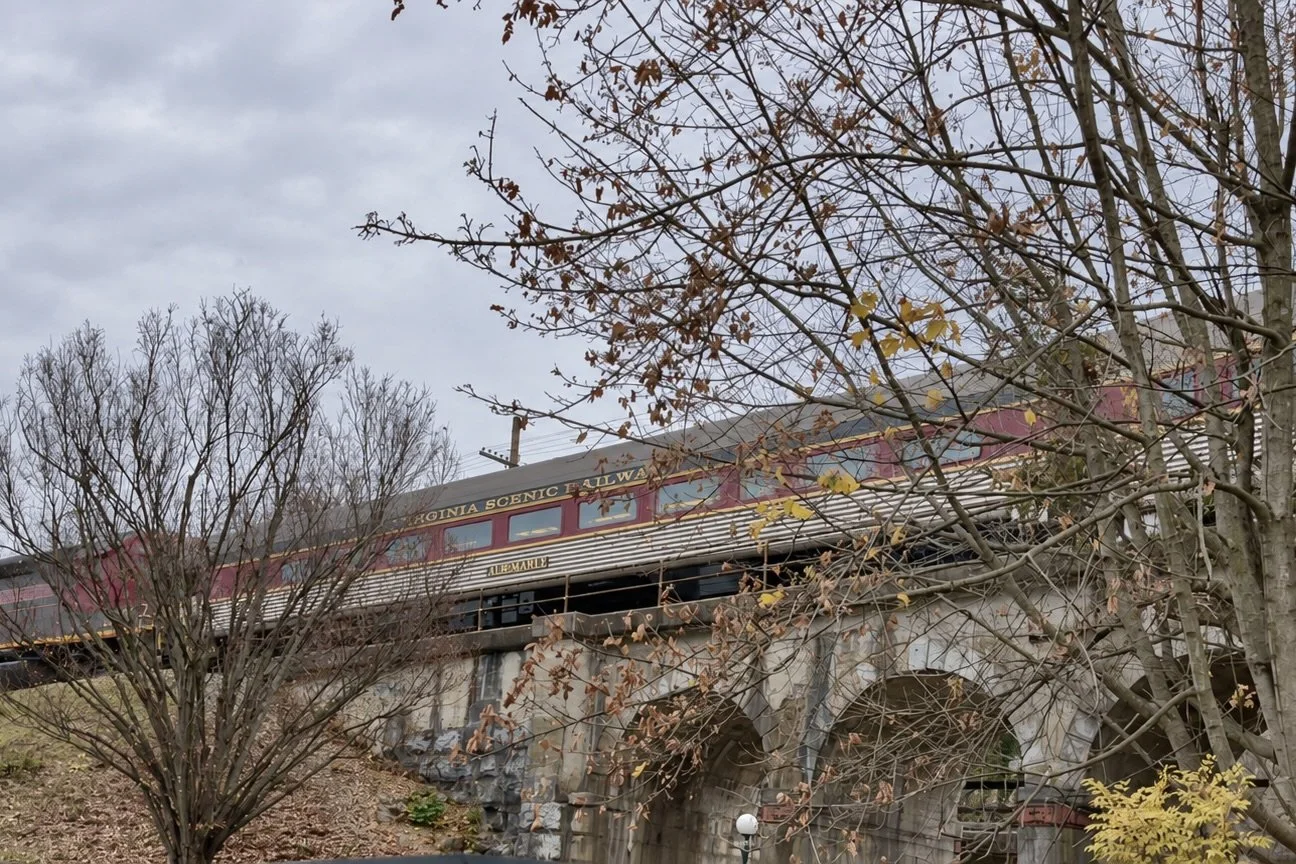 Virginia Scenic Railway train crossing a stone bridge above the stream near Crucible Coffee Roasters in Staunton.