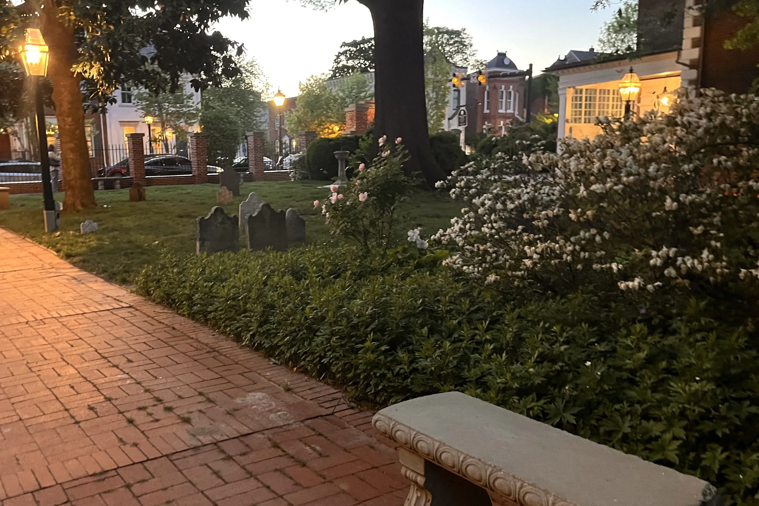Brick walkway at Christ Church in Old Town Alexandria at dusk, with a bench, garden beds, and a calm, low-traffic path.