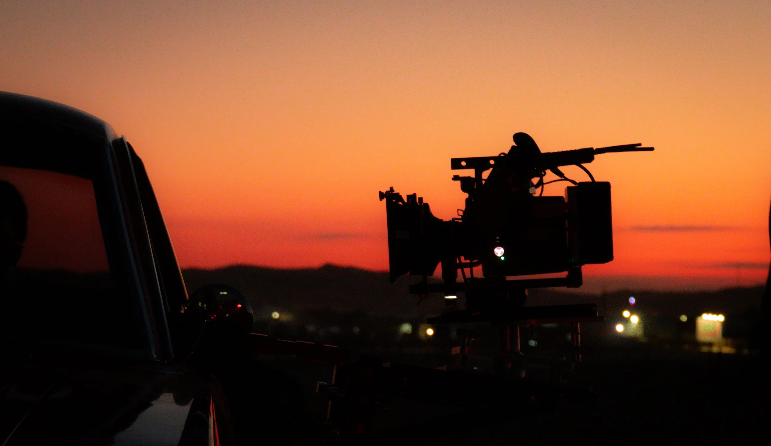 Silhouette of a military helicopter with mounted gun at sunset with a colorful sky in the background.