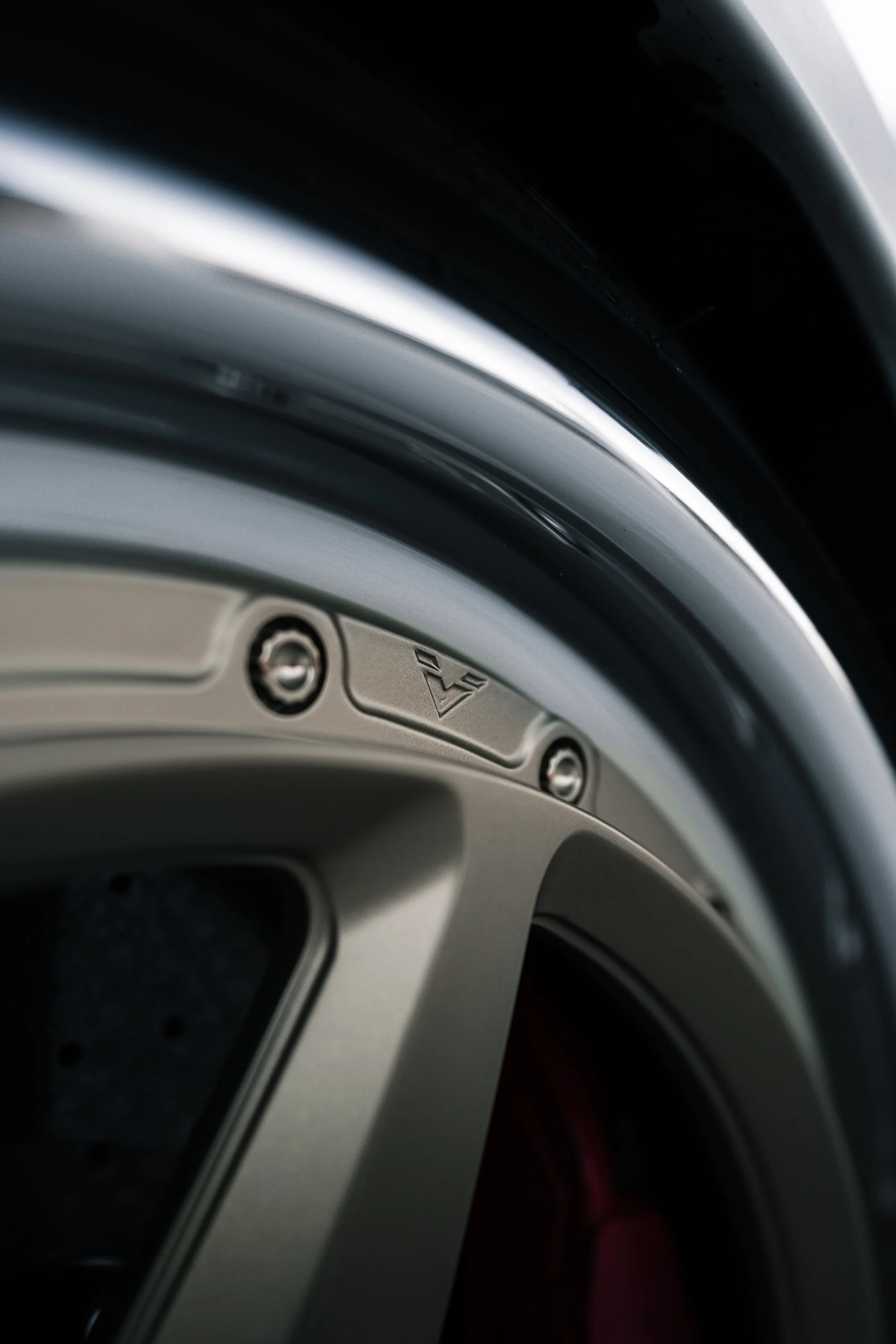 Close-up of a modern washing machine or dryer, showing part of the door frame and control panel with screws and a logo.