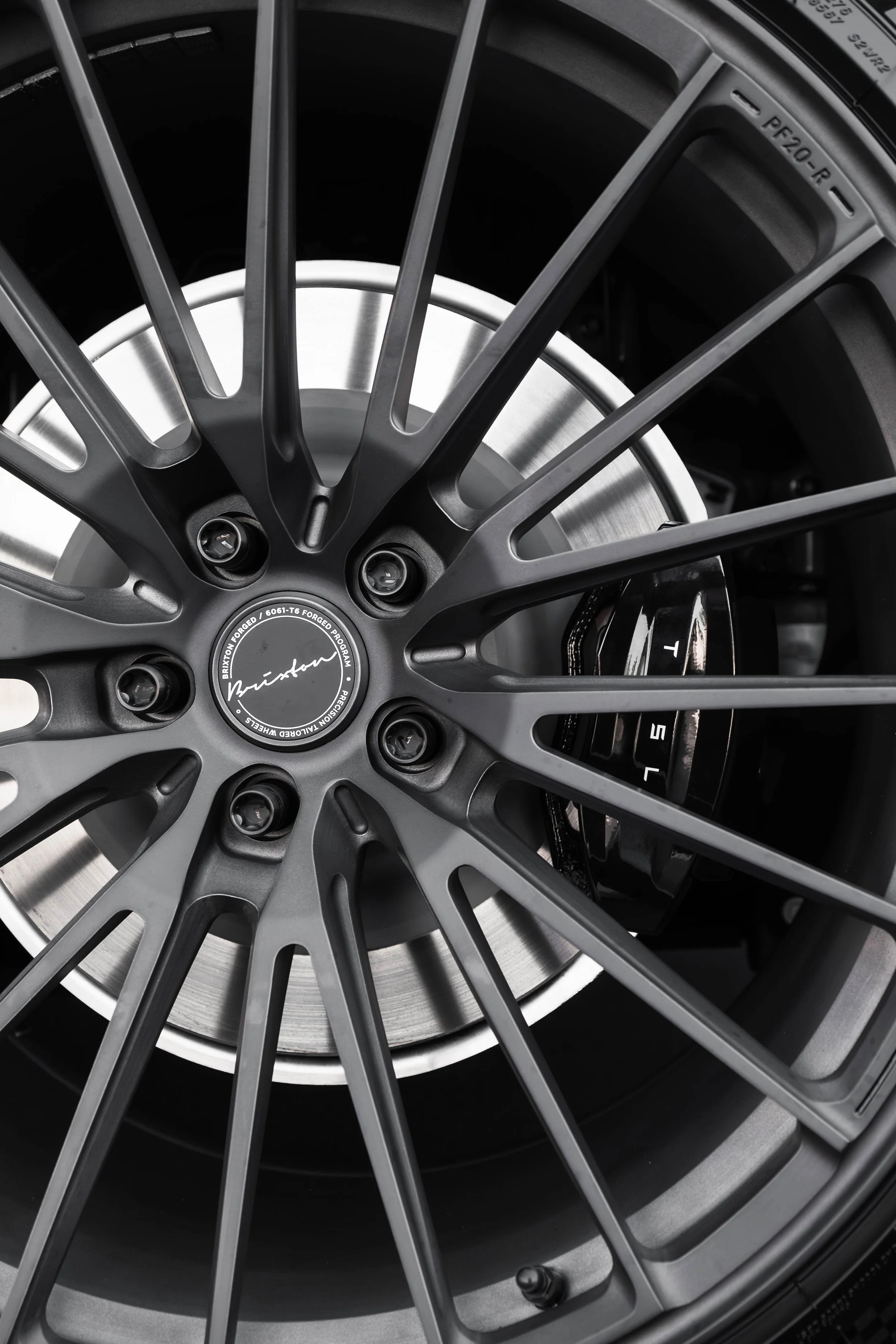 Close-up of a black alloy car wheel with multiple spokes and a silver brake disc behind it.