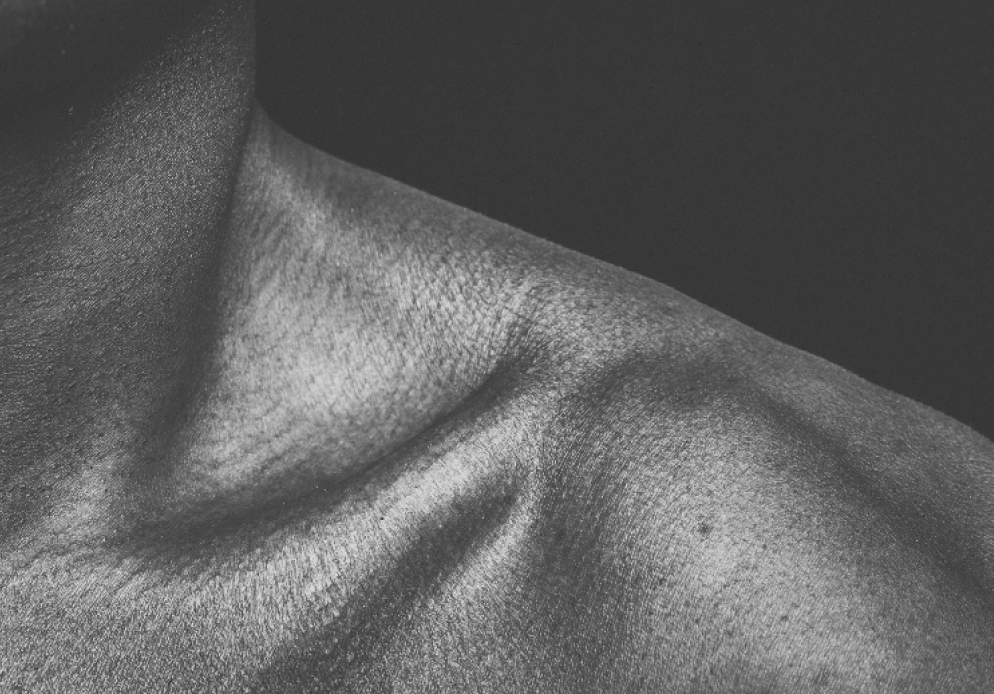 Close-up of a person's shoulder and neck area, with smooth skin and slight shadows, in black and white.