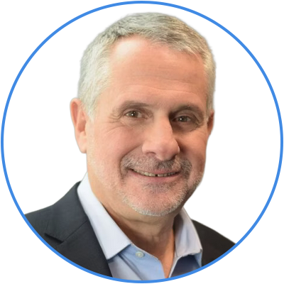 A portrait of a middle-aged man with short gray hair and a beard, smiling, wearing a navy suit and light blue shirt, against a plain white background.
