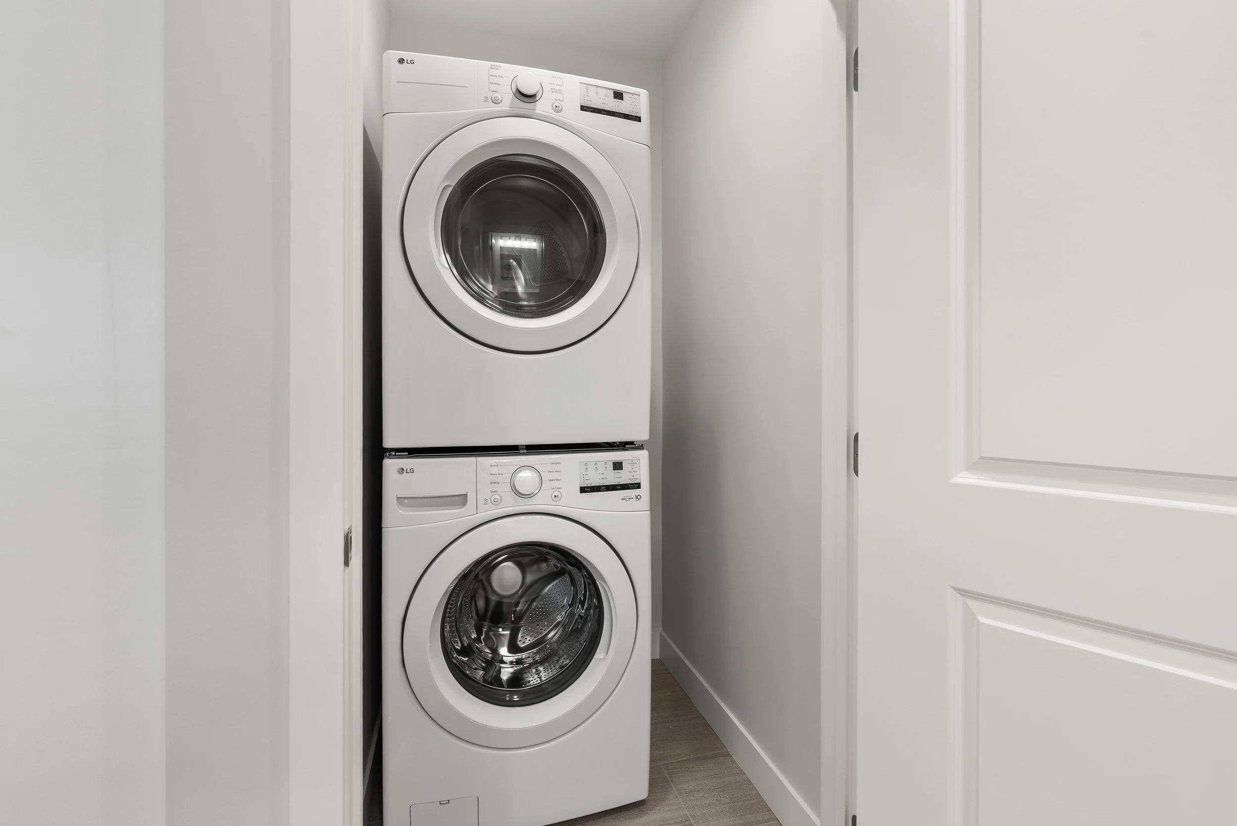 Stacked white LG washing machine and dryer in a small laundry closet.