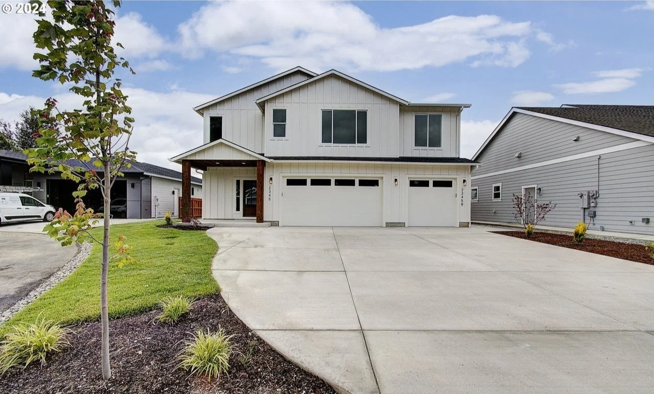Modern white two-story house with three-car garage and landscaped front yard
