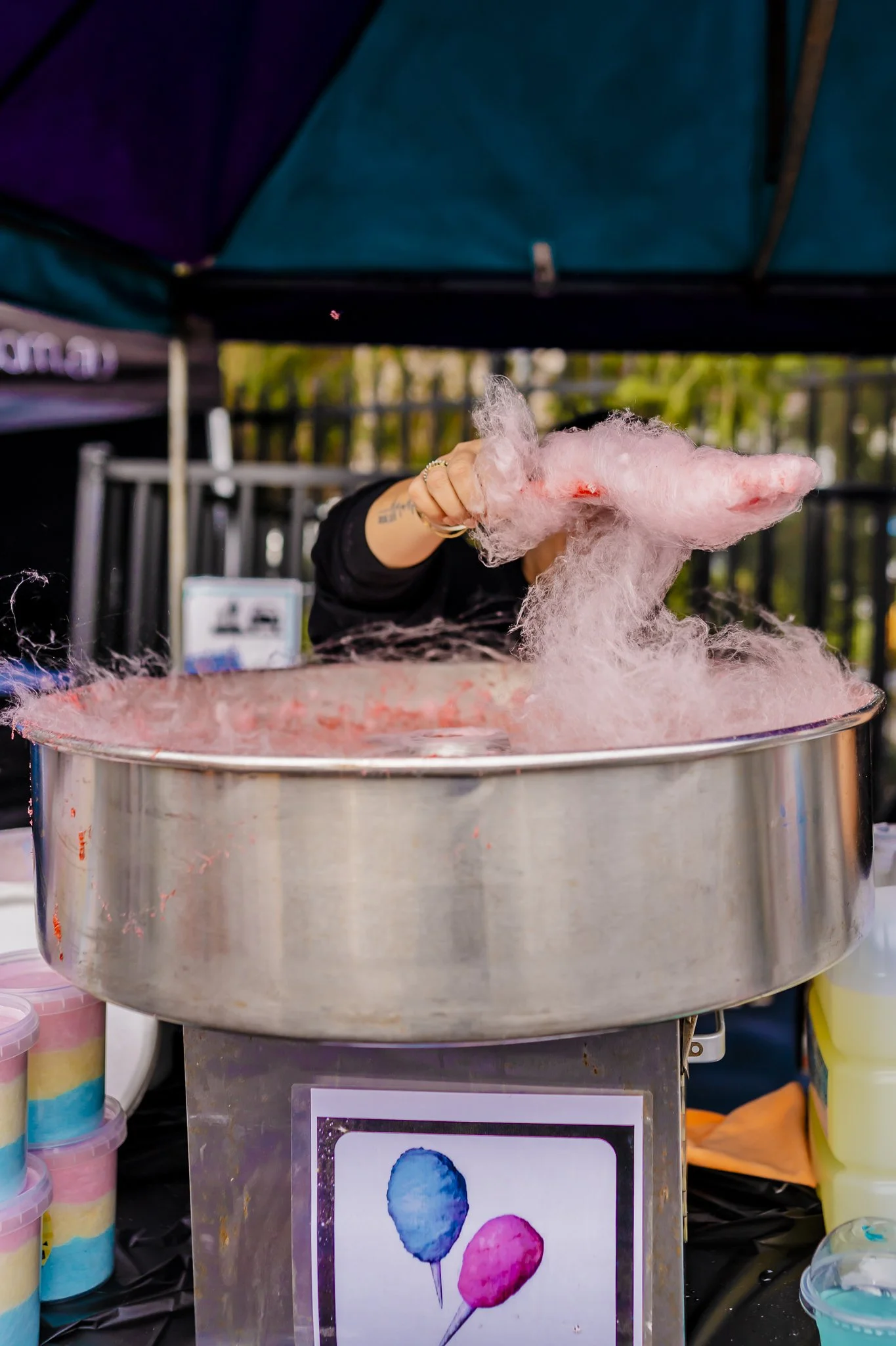 Pink cotton candy being made on a cotton candy machine at an outdoor event.