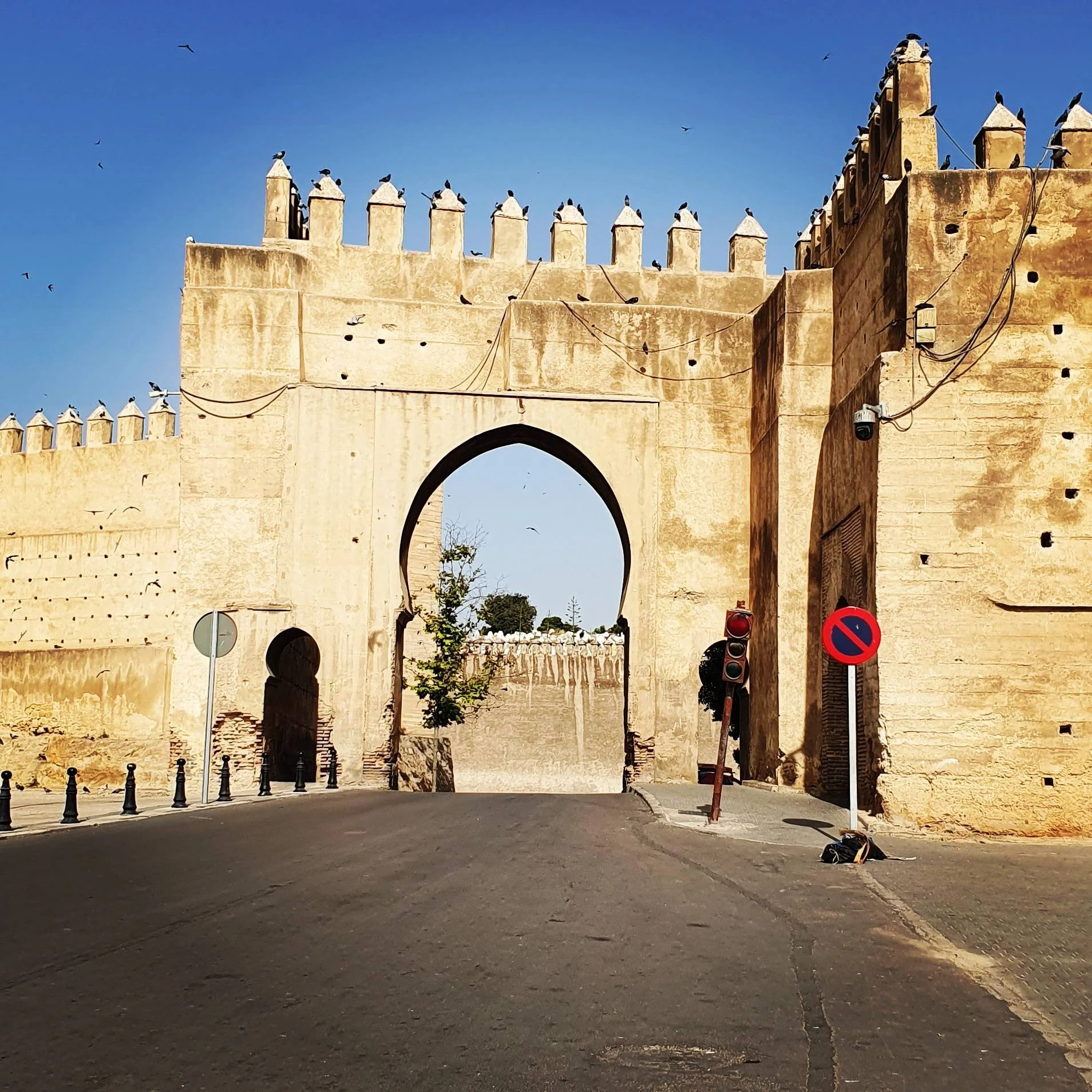 View of Bāb al-Futūḥ, the northern gate of Fez al-Bālī, Morocco, showing its Almohad-era horseshoe arch and surrounding rampart walls, with the open landscape beyond the city visible in the background.