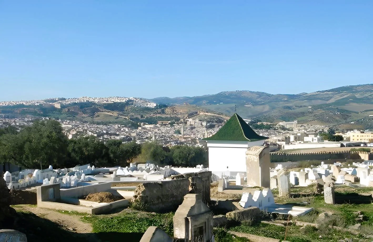 Aerial view of the whitewashed qubba of Mawlāy ʿAbd al-ʿAzīz al-Dabbāgh with its green pyramidal roof, set within the necropolis outside Bāb al-Futūḥ, Fez.