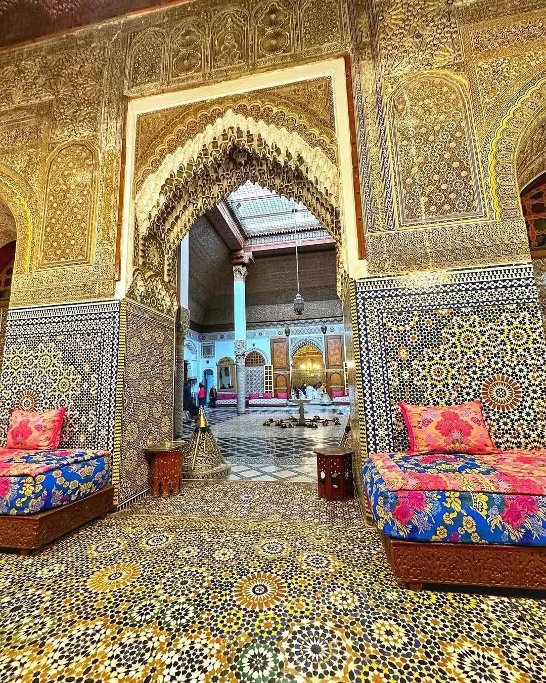 Close-up detail of Fāsī zellige geometric tilework in blue, white, and terracotta, showing interlocking star and polygon patterns characteristic of Moroccan sacred architecture.