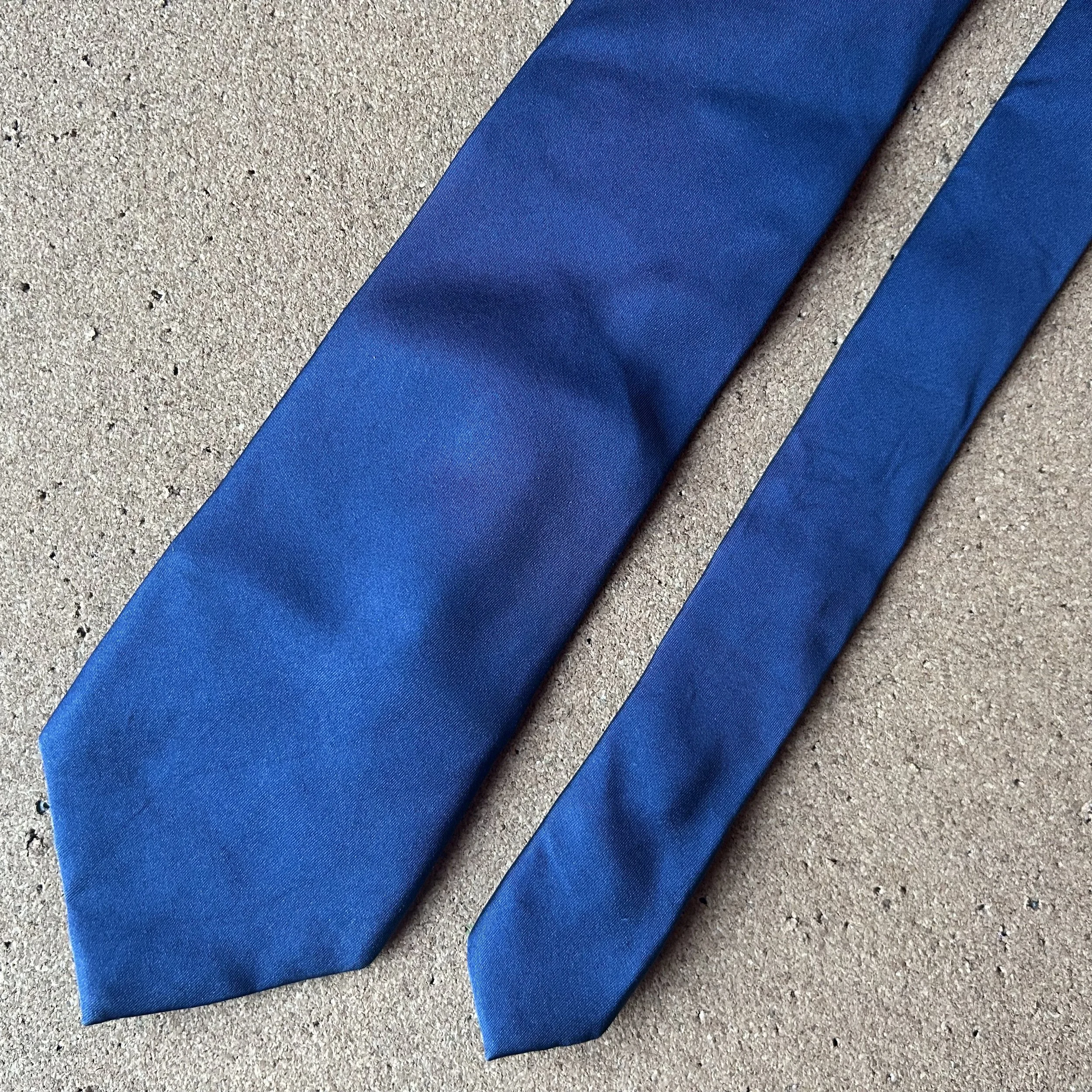 Blue necktie on a textured beige surface.