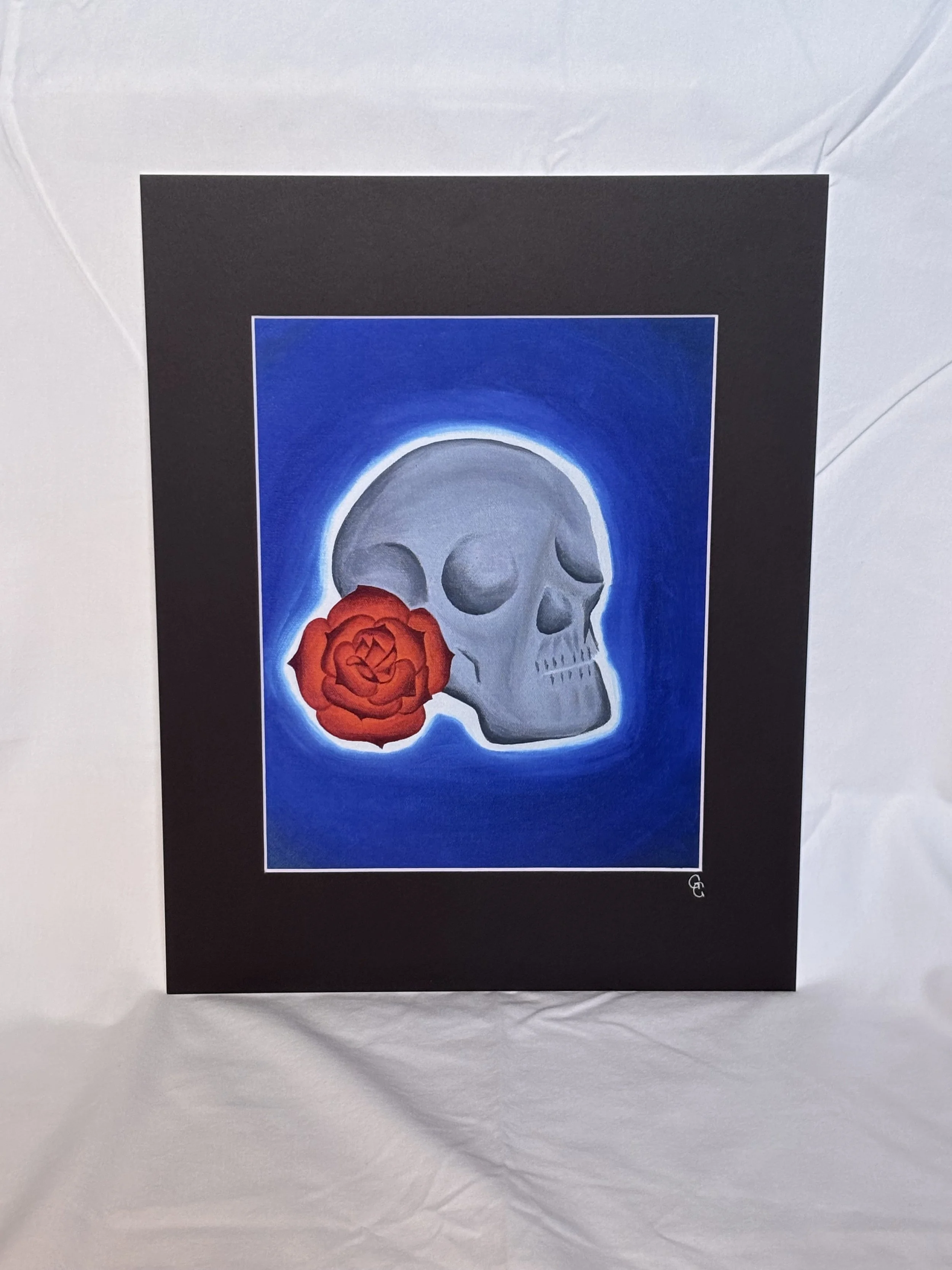 Art print of a skull with a red rose on a blue background with black mat border