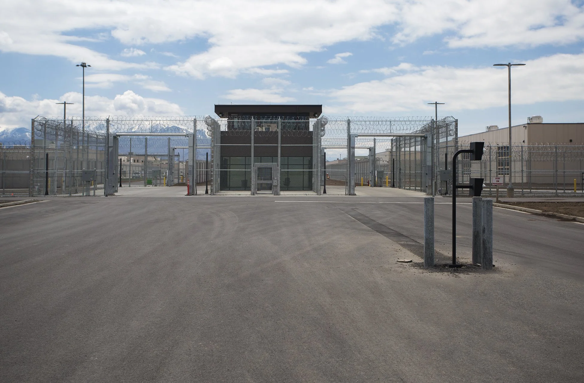View of a secure industrial or military facility with fences and a guard building, under partly cloudy sky.