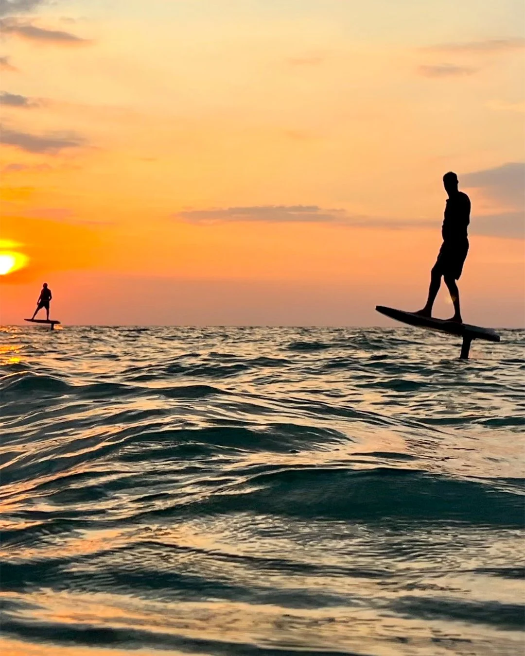Silhouette of people eFoiling at sunset