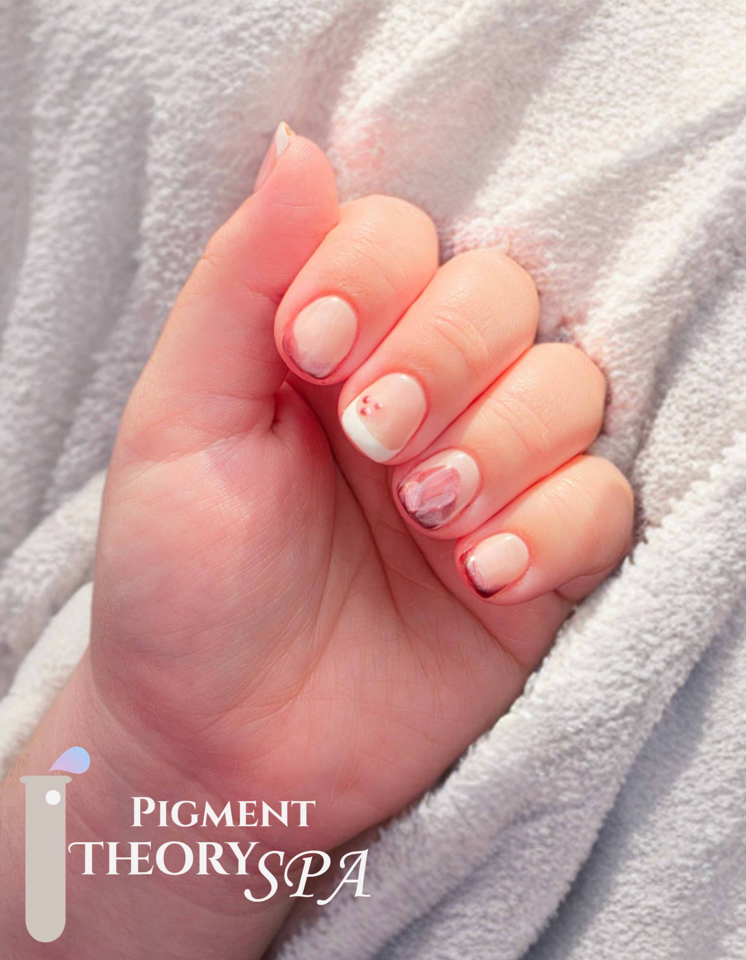 Close-up of a hand with natural nails resting on soft fabric, with a nail art design featuring small red dots.