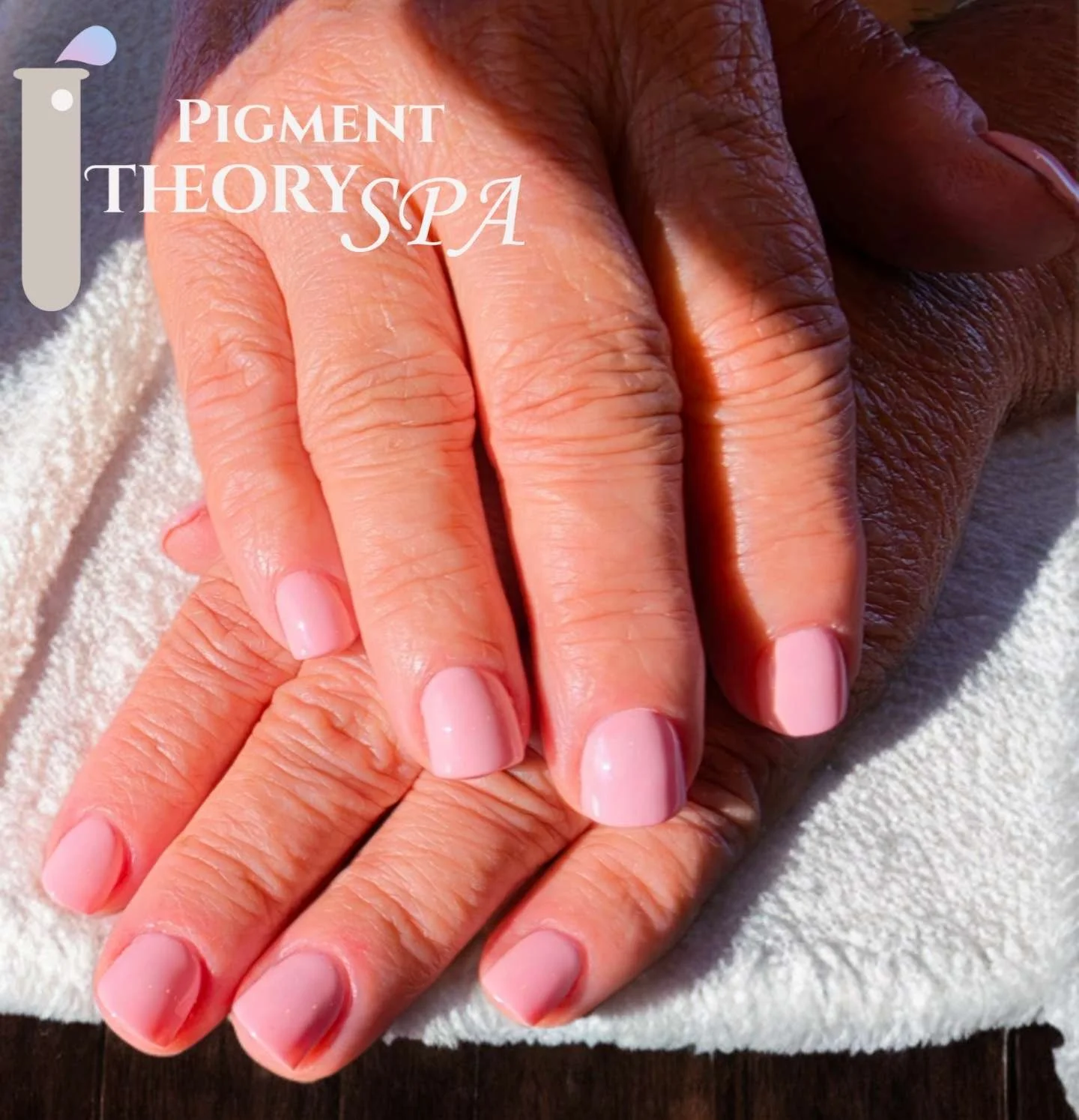 Close-up of hands with manicured nails on a white towel, showing skin tone and texture. Text overlay reads 'Pigment Theory Spa'.