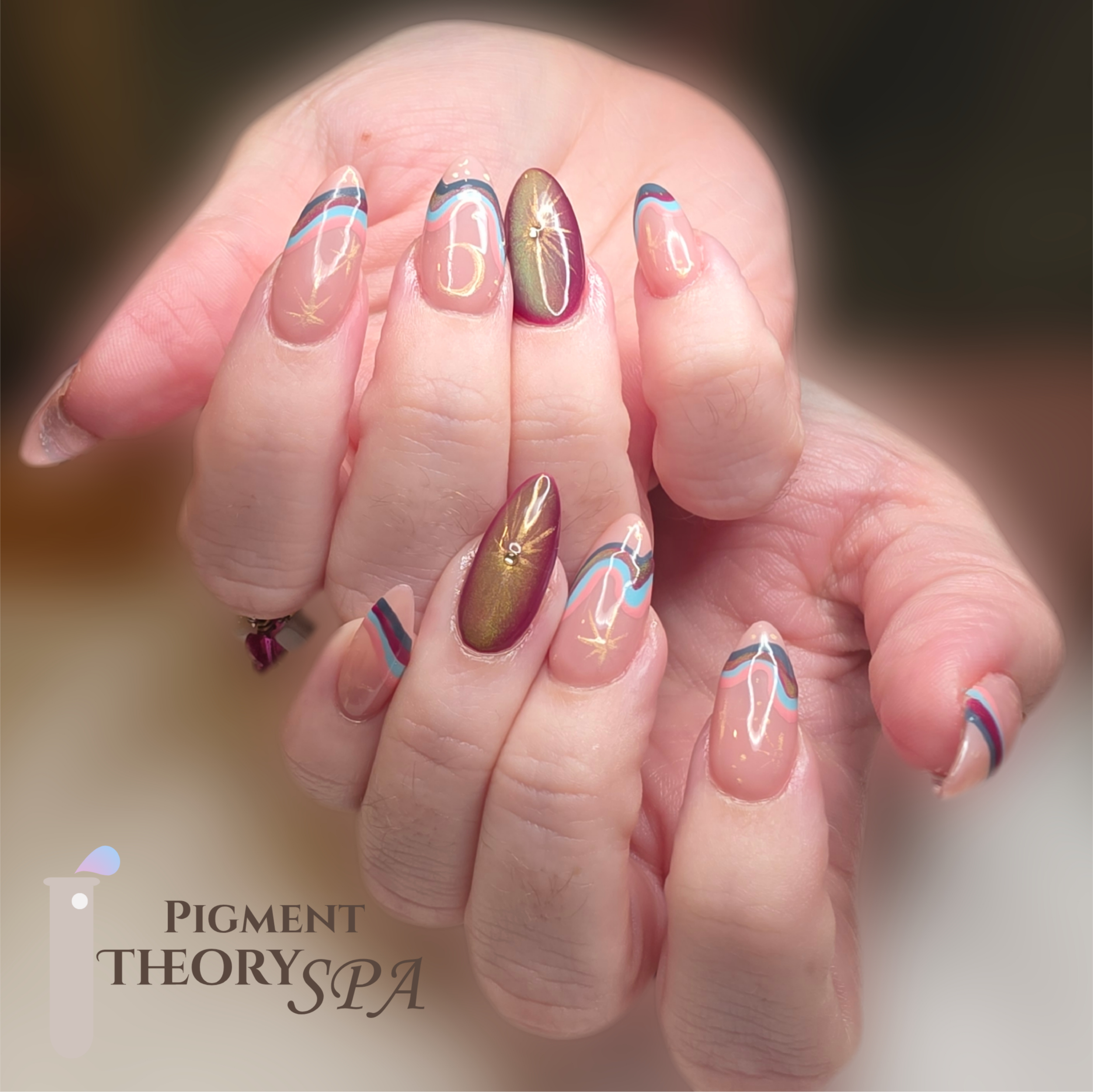Close-up of a hand with pastel-colored abstract nail art on fingernails, with gold accents