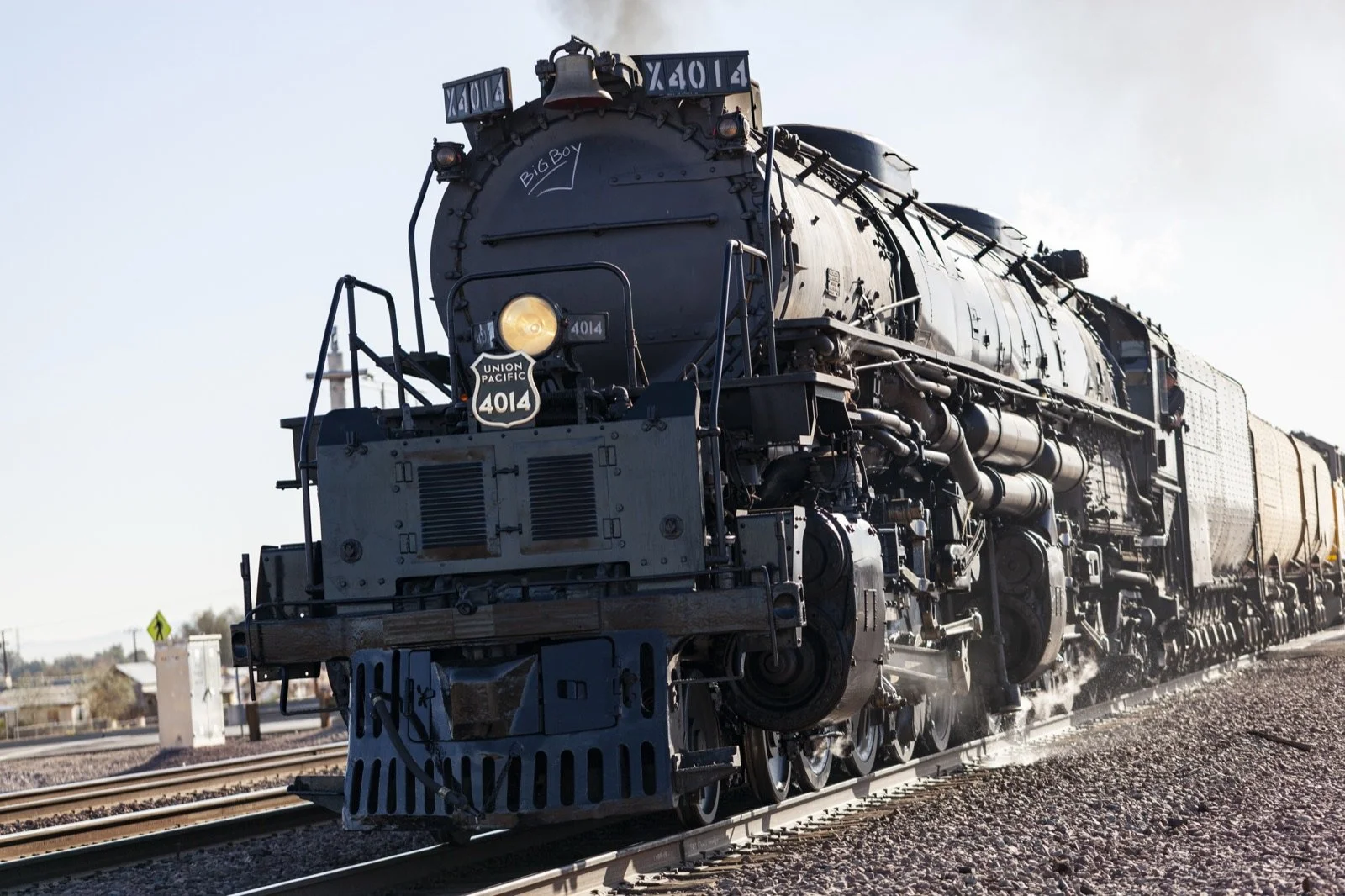 A black steam locomotive numbered 4014 traveling on railroad tracks, with a Union Pacific logo on the front, under a clear sky.