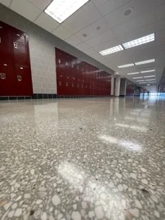 Empty hallway with red lockers and tiled floor in a school