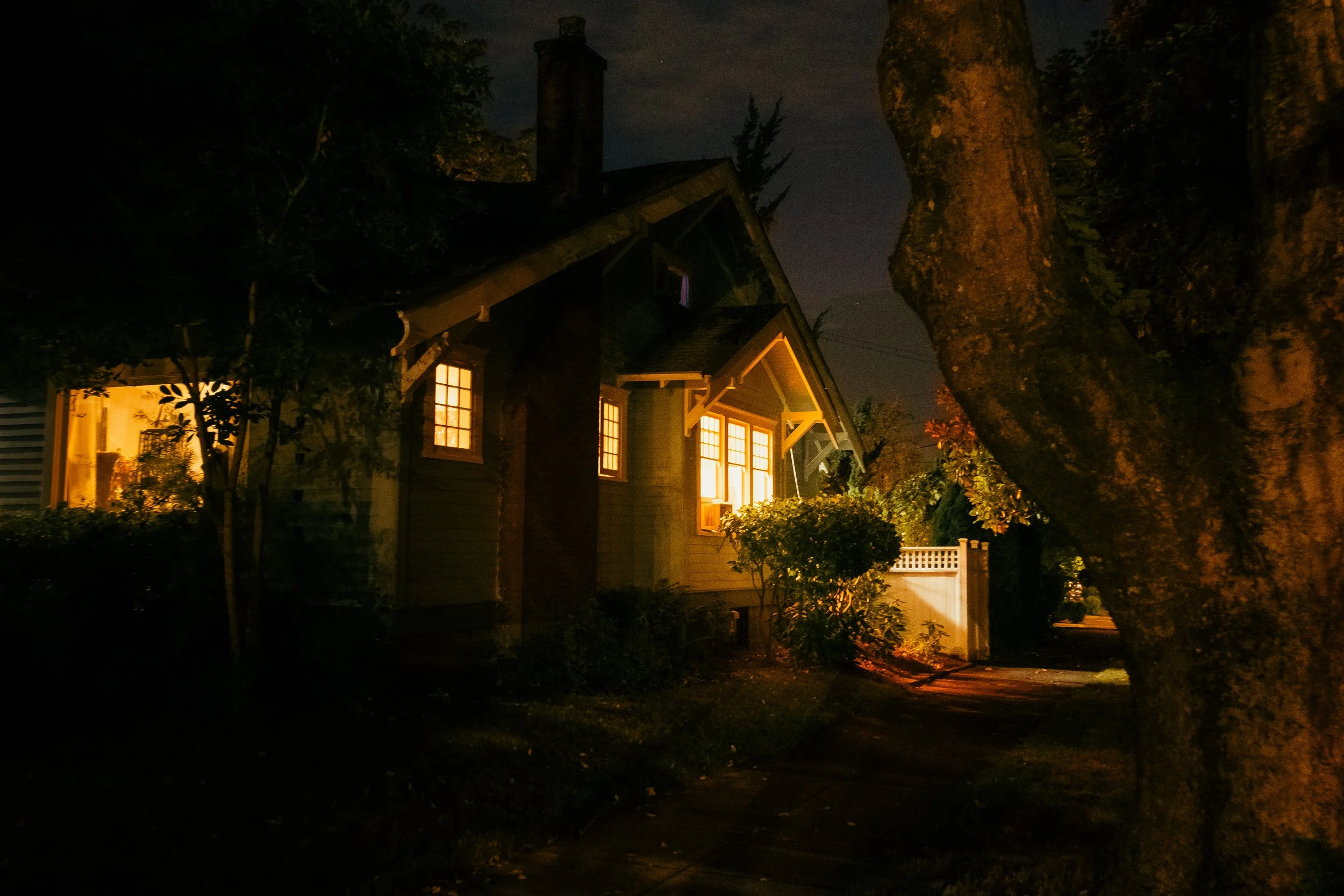 The Night By AJ Miranda Low-light, cinematic photograph of historic Vancouver, WA architecture during blue hour, using ambient light and deep chiaroscuro shadows to create an eerie film aesthetic.