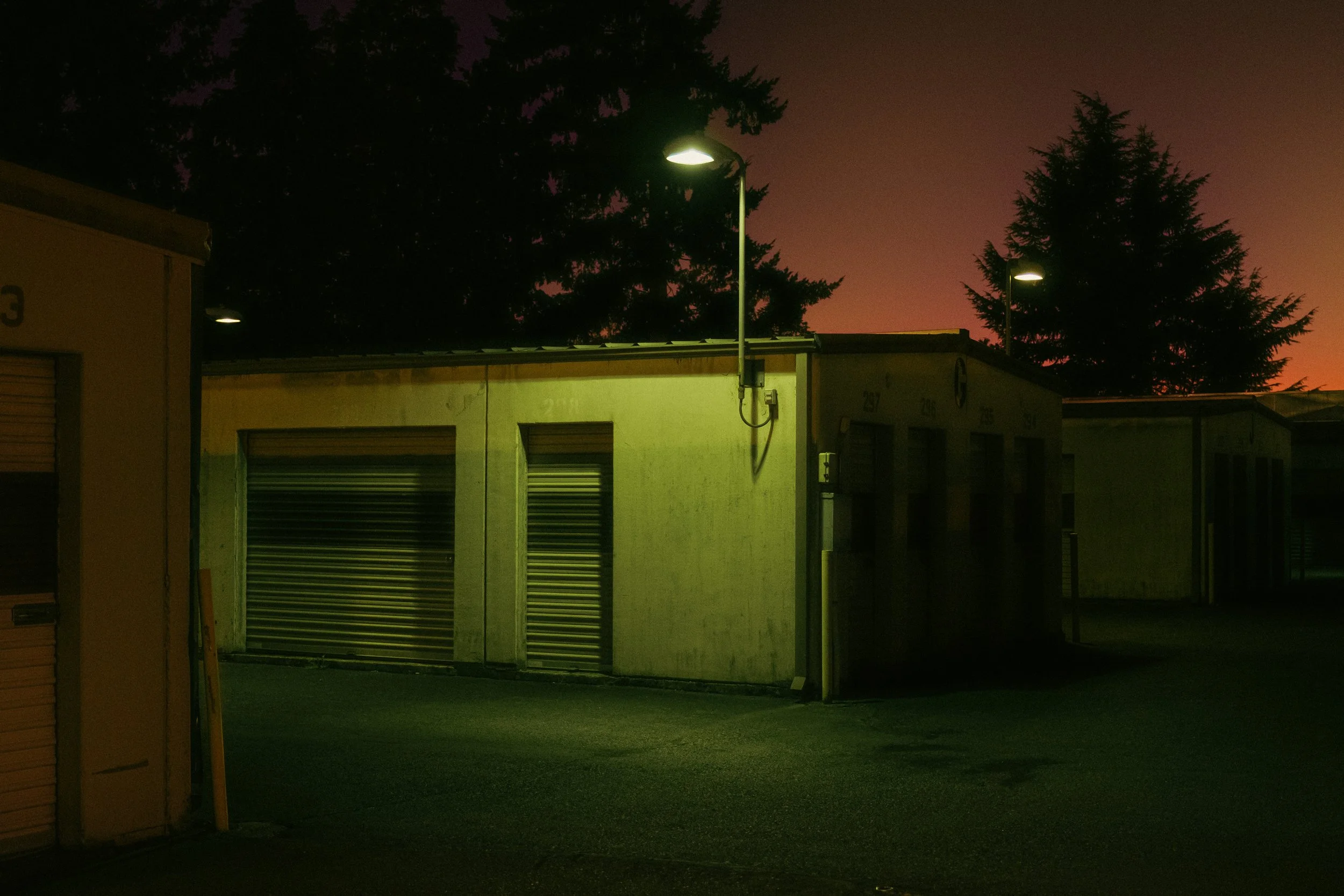 The Night By AJ Miranda Low-light, cinematic photograph of historic Vancouver, WA architecture during blue hour, using ambient light and deep chiaroscuro shadows to create an eerie film aesthetic.