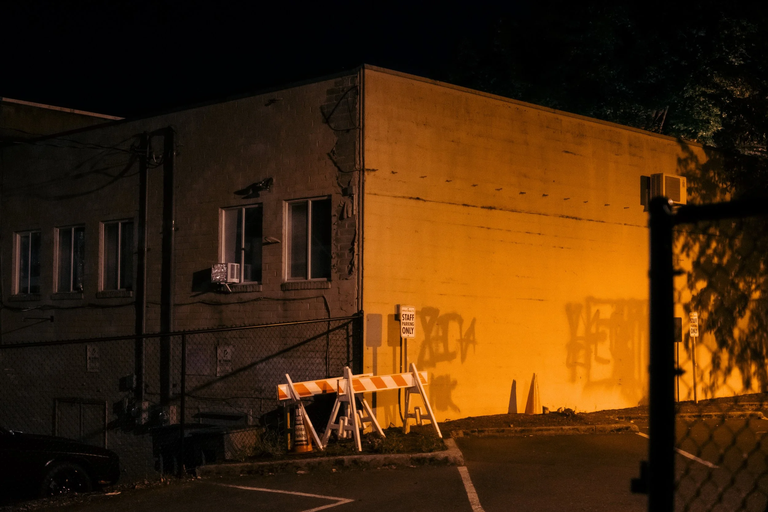 The Night By AJ Miranda Low-light, cinematic photograph of historic Vancouver, WA architecture during blue hour, using ambient light and deep chiaroscuro shadows to create an eerie film aesthetic.