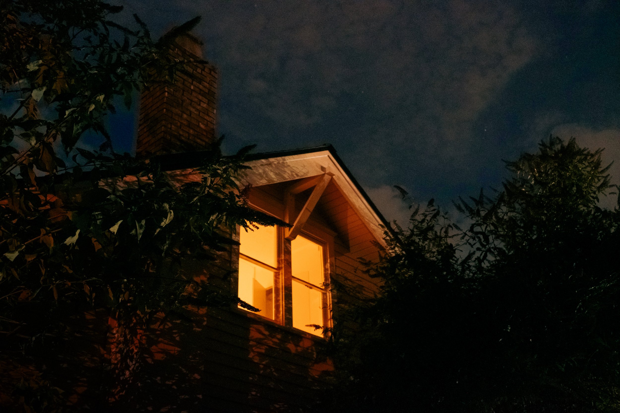The Night By AJ Miranda Low-light, cinematic photograph of historic Vancouver, WA architecture during blue hour, using ambient light and deep chiaroscuro shadows to create an eerie film aesthetic.