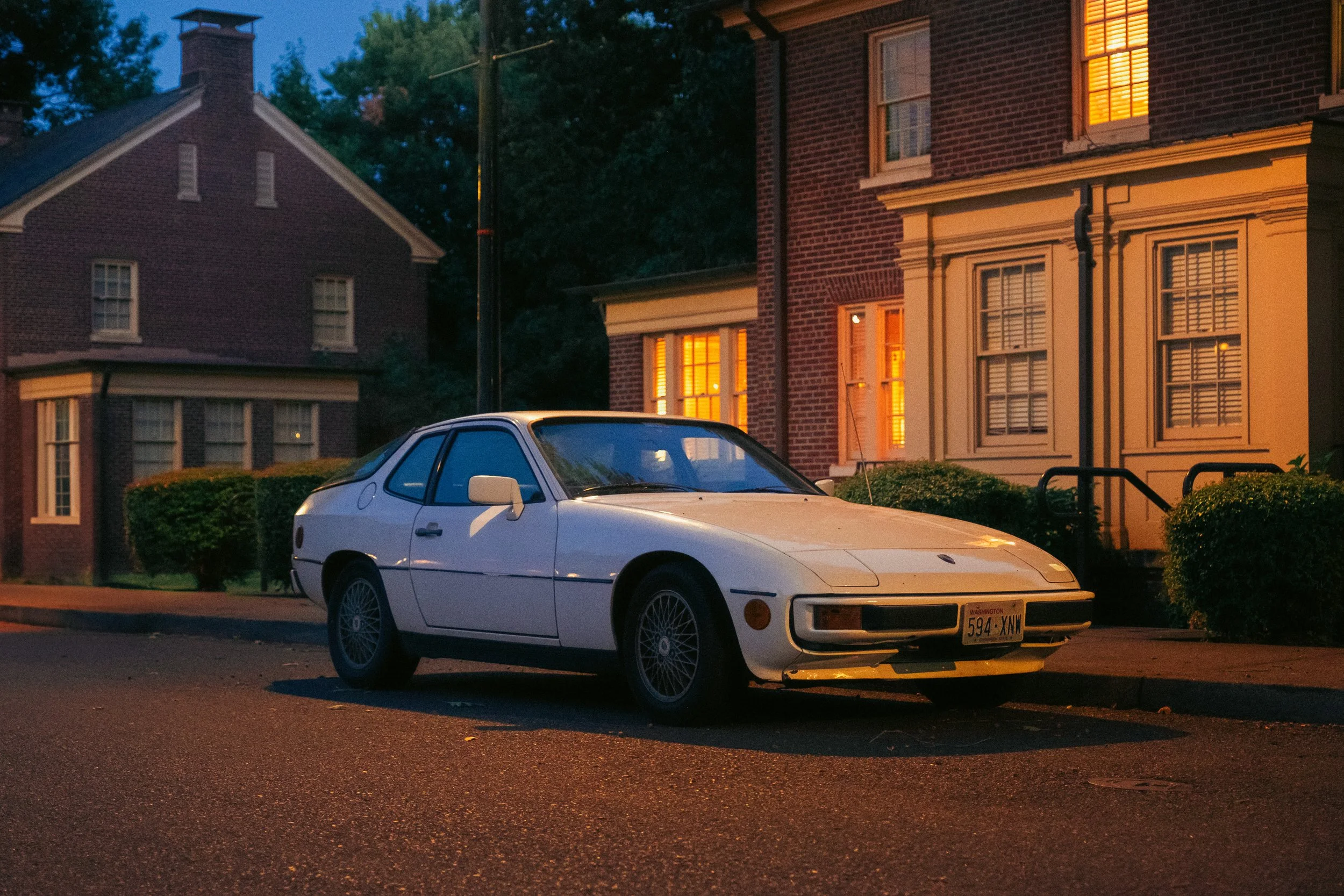 The Night By AJ Miranda Low-light, cinematic photograph of historic Vancouver, WA architecture during blue hour, using ambient light and deep chiaroscuro shadows to create an eerie film aesthetic.