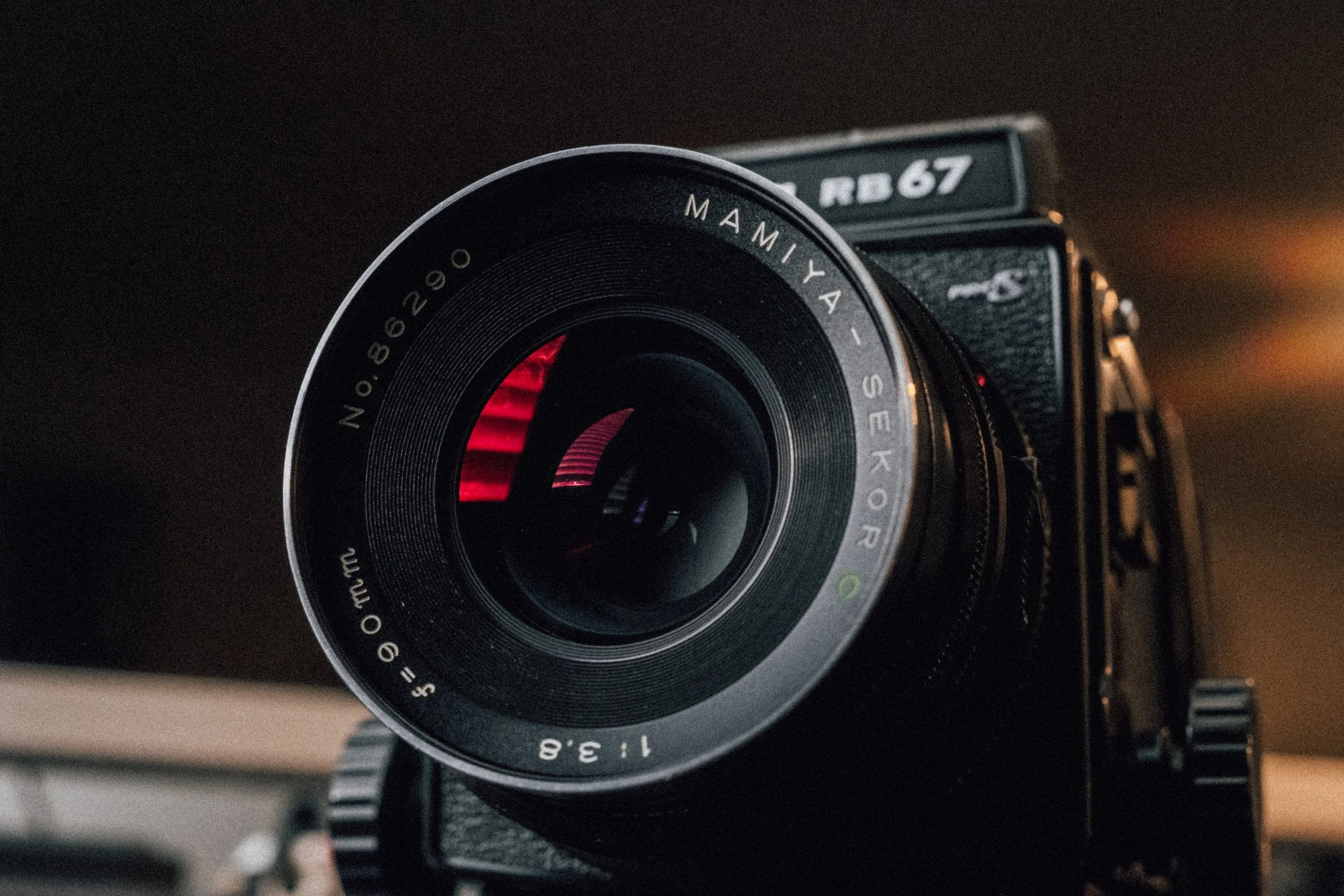 Close-up of a vintage camera with a large lens labeled Мамия-Se Kodak, with reflections visible in the glass element of the lens.