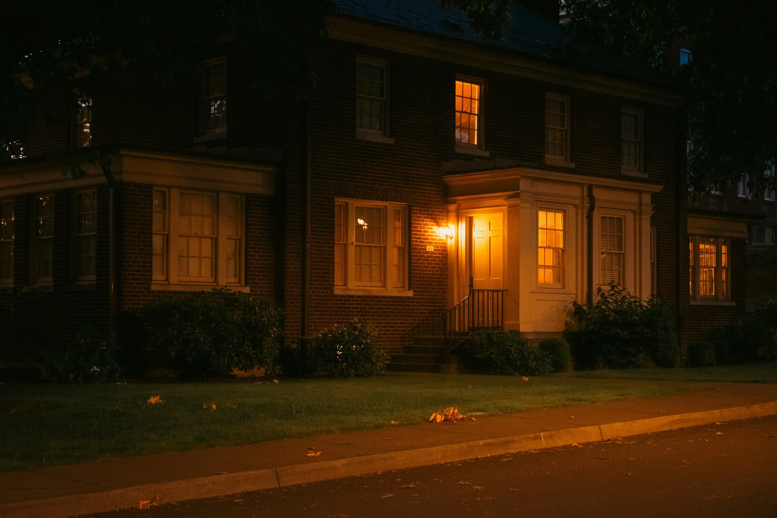 The Night By AJ Miranda Low-light, cinematic photograph of historic Vancouver, WA architecture during blue hour, using ambient light and deep chiaroscuro shadows to create an eerie film aesthetic.