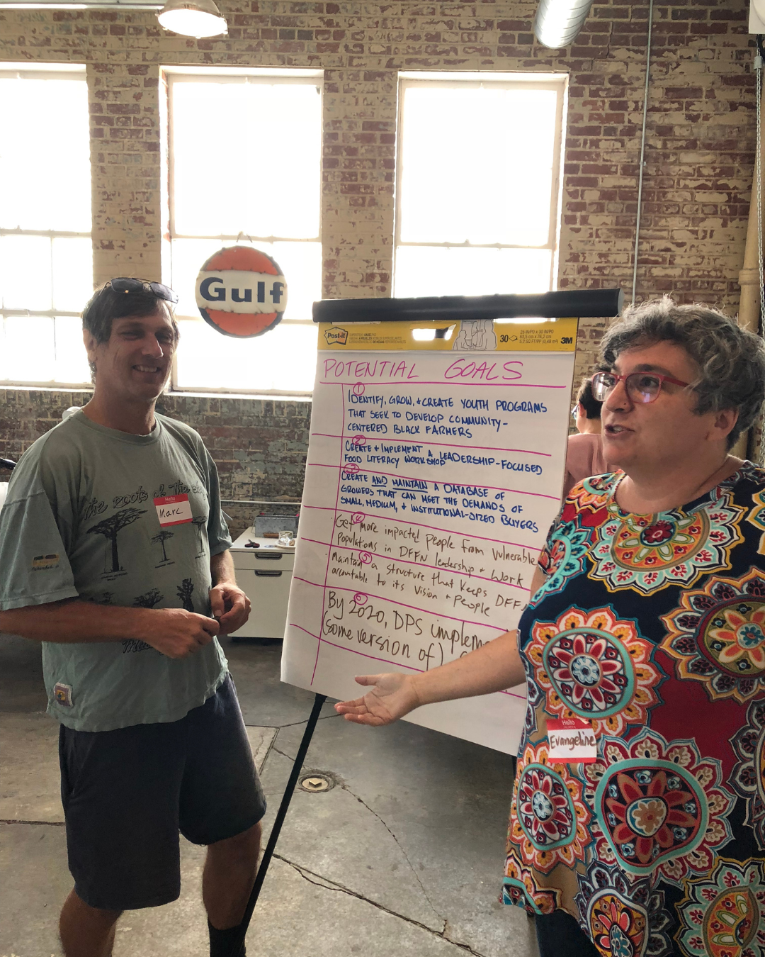 Evangeline Weiss Consulting | A woman is presenting a large poster with handwritten notes titled 'Potential Goals' at a workshop.