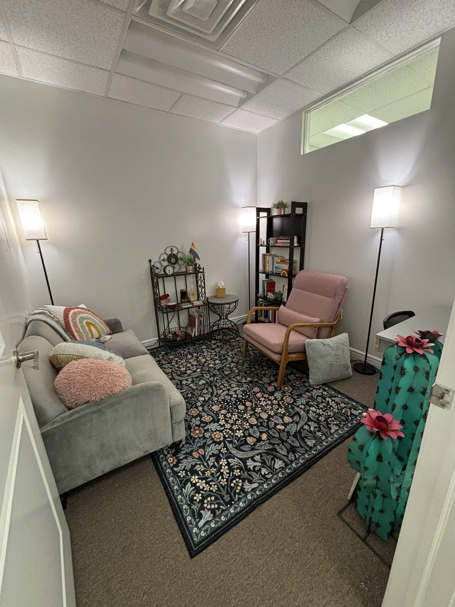 Calm, confidential, softly lit therapy office viewed from the doorway designed to support safety, comfort, and emotional regulation