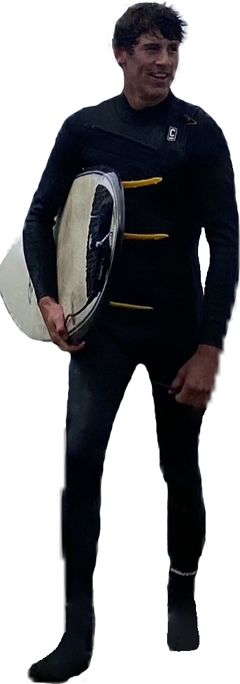 A young man in a wetsuit holding a surfboard under his arm, standing outdoors.