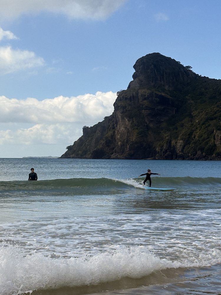 A young surfer riding a wave at Taupō Bay