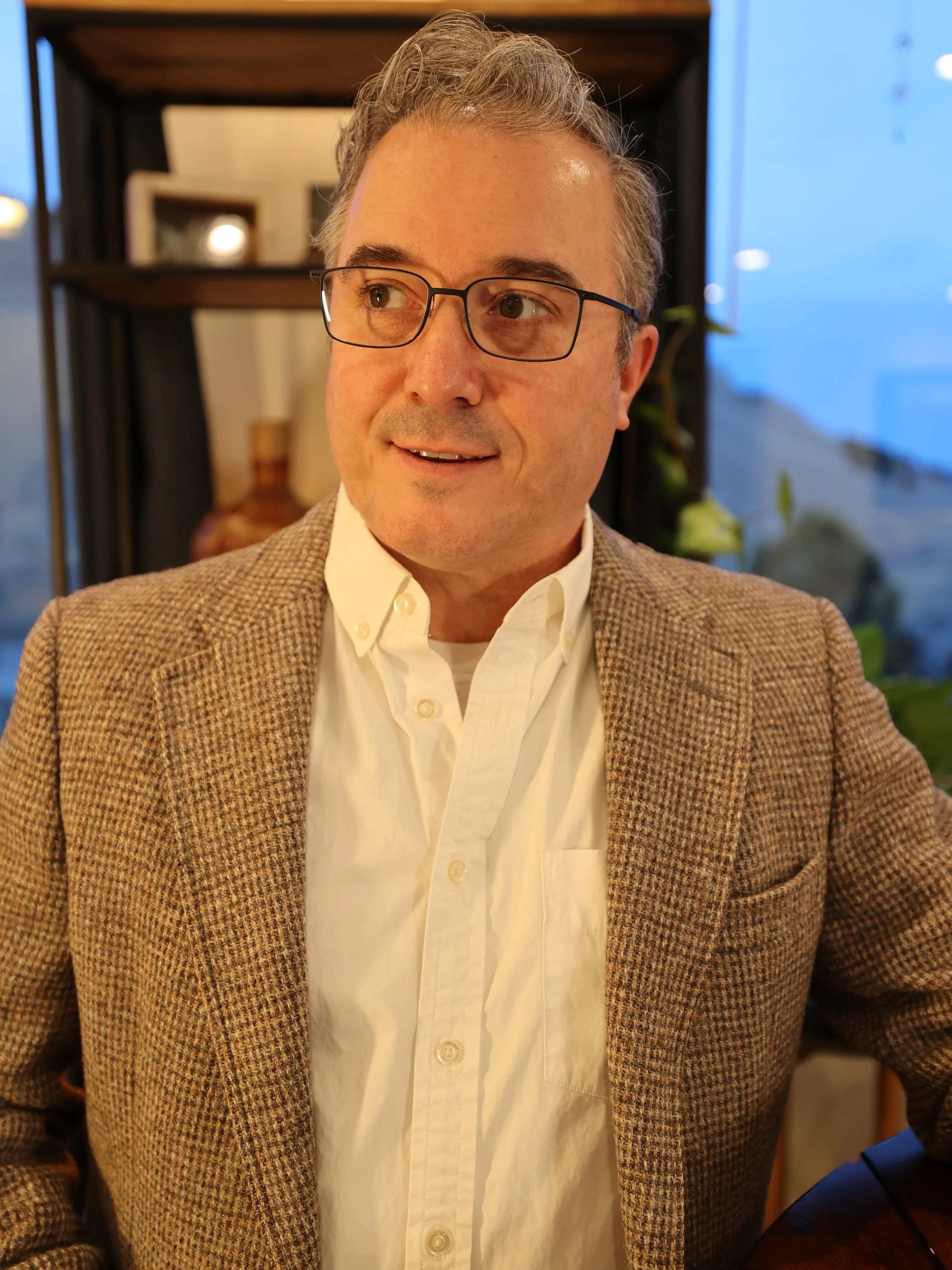 Portrait of Daniel Cameron on the About page, wearing a jacket and glasses in a professional indoor setting.