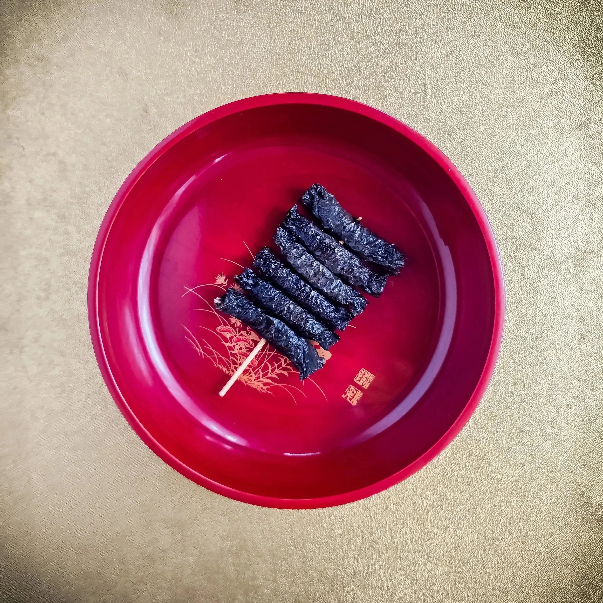 赤い皿の上に志そ巻（しそ巻）が置かれている